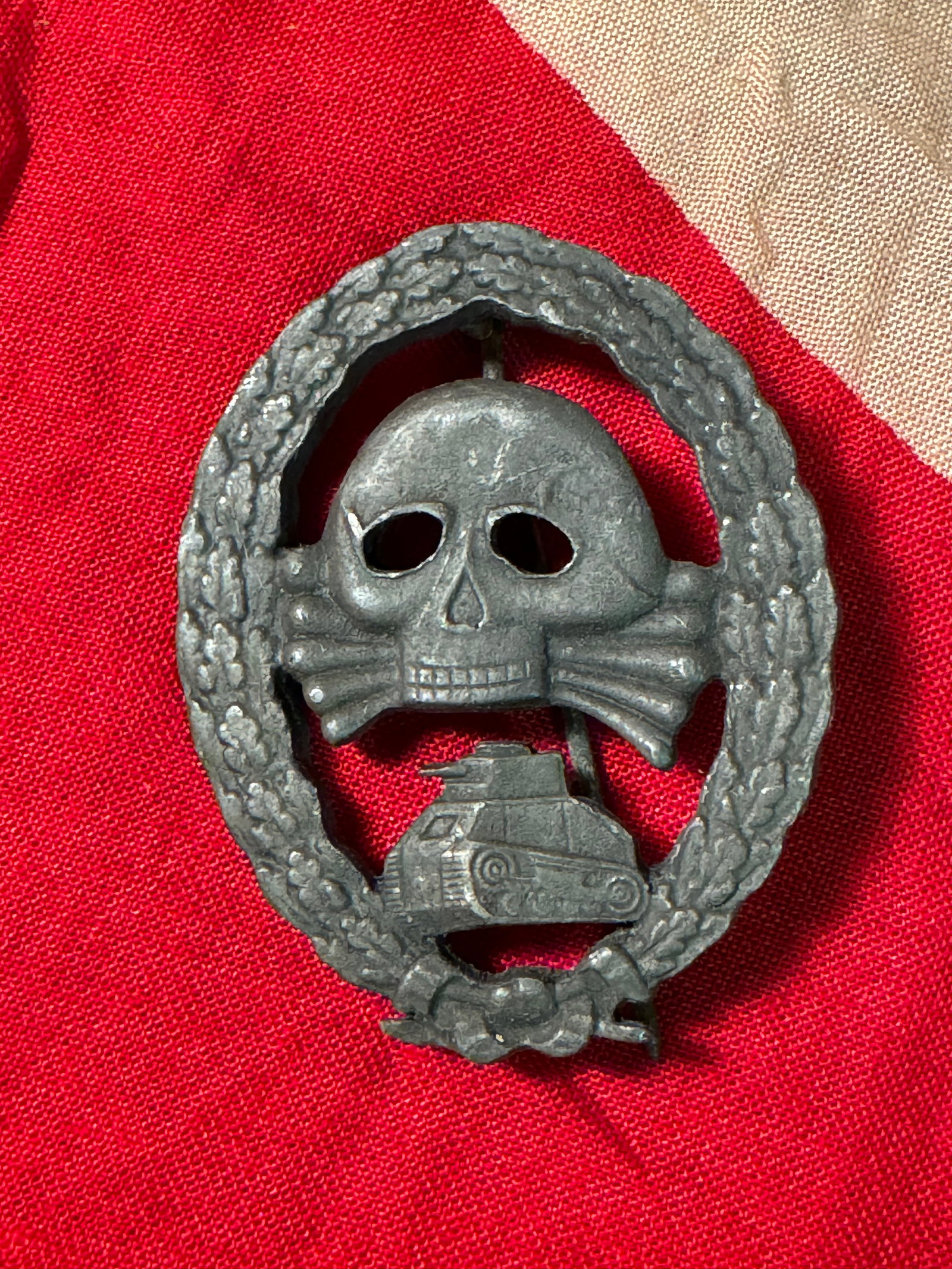 WWII GERMAN CONDOR LEGION TANK ASSAULT BADGE: German WWII Spanish Condor Legion Tank Assault Badge. Measures 1 7/8 X 2 3/8 inches. Front shows a Totenkopf in the center with a tank below surrounded by an oval oak leaf wreath. Thin vertical pin ba