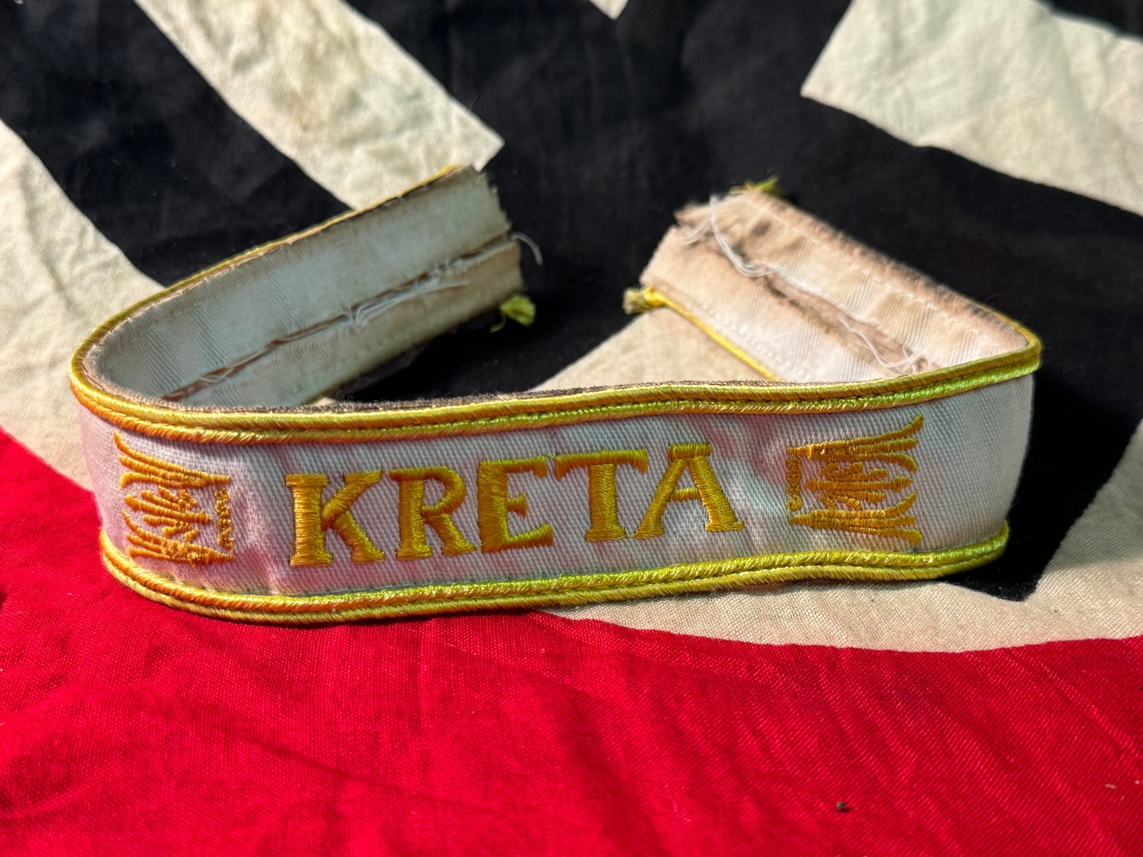 German WWII Kreta Campaign Cufftitle - Uniform Cut Off: German WWII Kreta Campaign Cufftitle - Uniform Cut Off. This is a nice but well worn Kreta Campaign Cuff title which was removed from a uniform. It is white cotton construction with machine embroidere