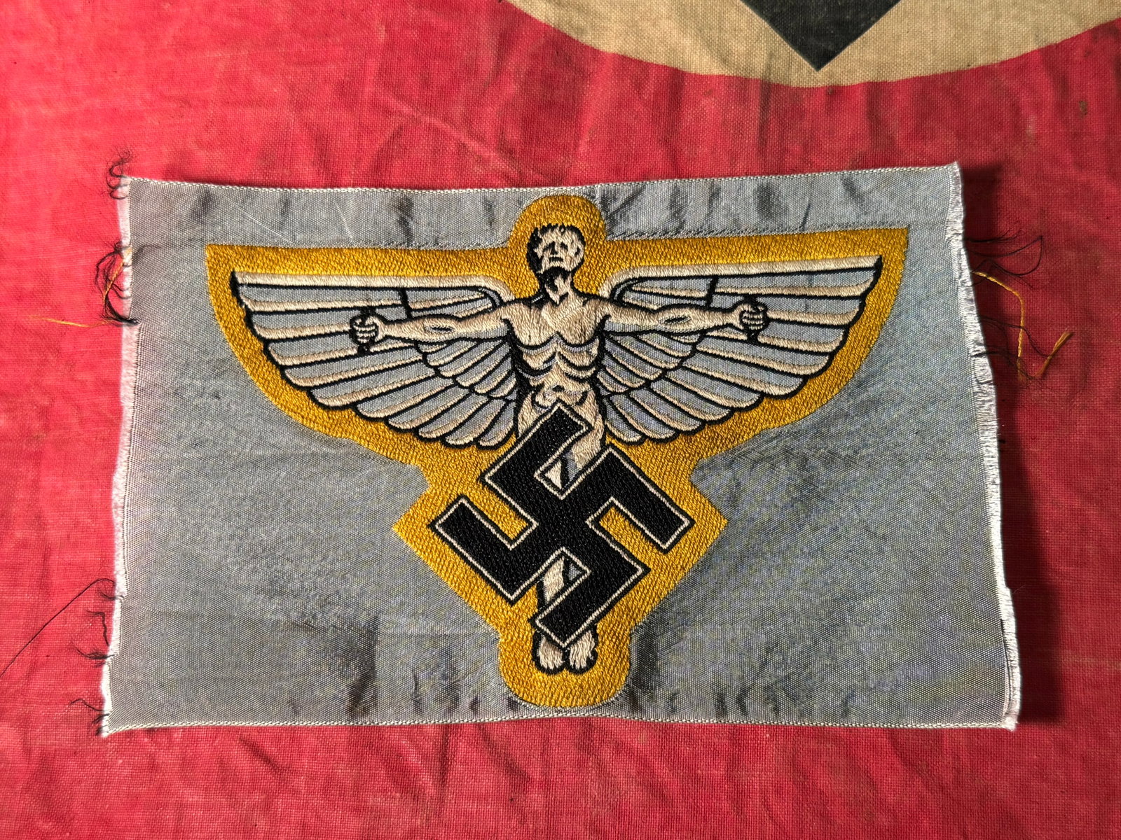 WW2 GERMAN N.S.F.K. SPORTS VEST BADGE: WW2 GERMAN N.S.F.K. SPORTS VEST BADGE. A RARE FIND. SHOWS GOOD WEAR AND USE WITH A BEAUTIFUL OVERALL PATINA. FINE QUALITY UN-CUT BEVO BADGE FOR THE SPORTS VEST. 145 BY 95 MM. SOME CREASES. NO DAMAGE.
