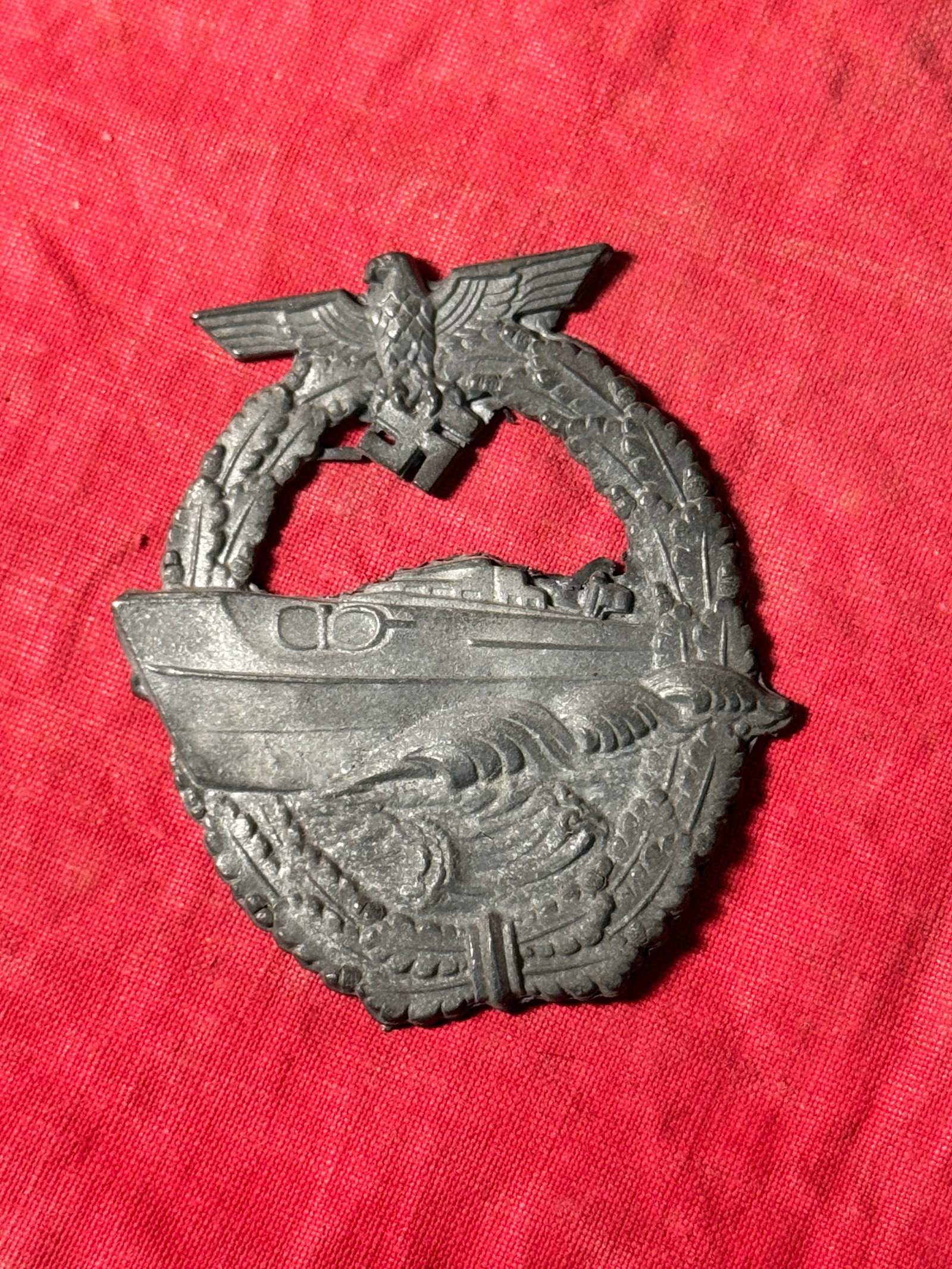 WW2 GERMAN KRIESMARINE SCHNELLBOOT E-BOAT BADGE: WW2 GERMAN KRIESMARINE SCHNELLBOOT E-BOAT BADGE. Die struck second pattern S-boat badge. The badge is in the form of a vertically oval oak-leaf wreath with a small national eagle with out-stretched wi