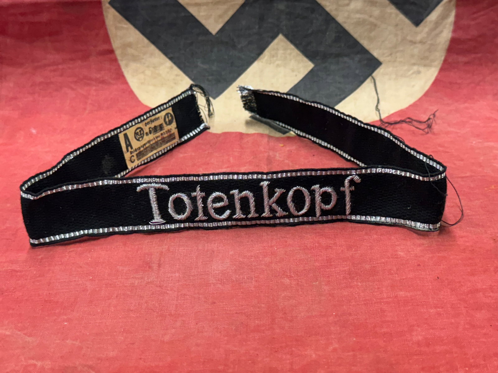 RARE WW2 GERMAN TOTENKOPF SS OFFICER CUFF TITLE WITH RZM PAPER TAG: RARE WW2 GERMAN TOTENKOPF SS OFFICER CUFF TITLE WITH RZM PAPER TAG. A RARE EXAMPLE. SHOWS GOOD WEAR AND USE WITH A BEAUTIFUL PATINA THROUGHOUT. PLEASE VIEW ALL DETAILED PICTURES. A SCARCE ITEM.