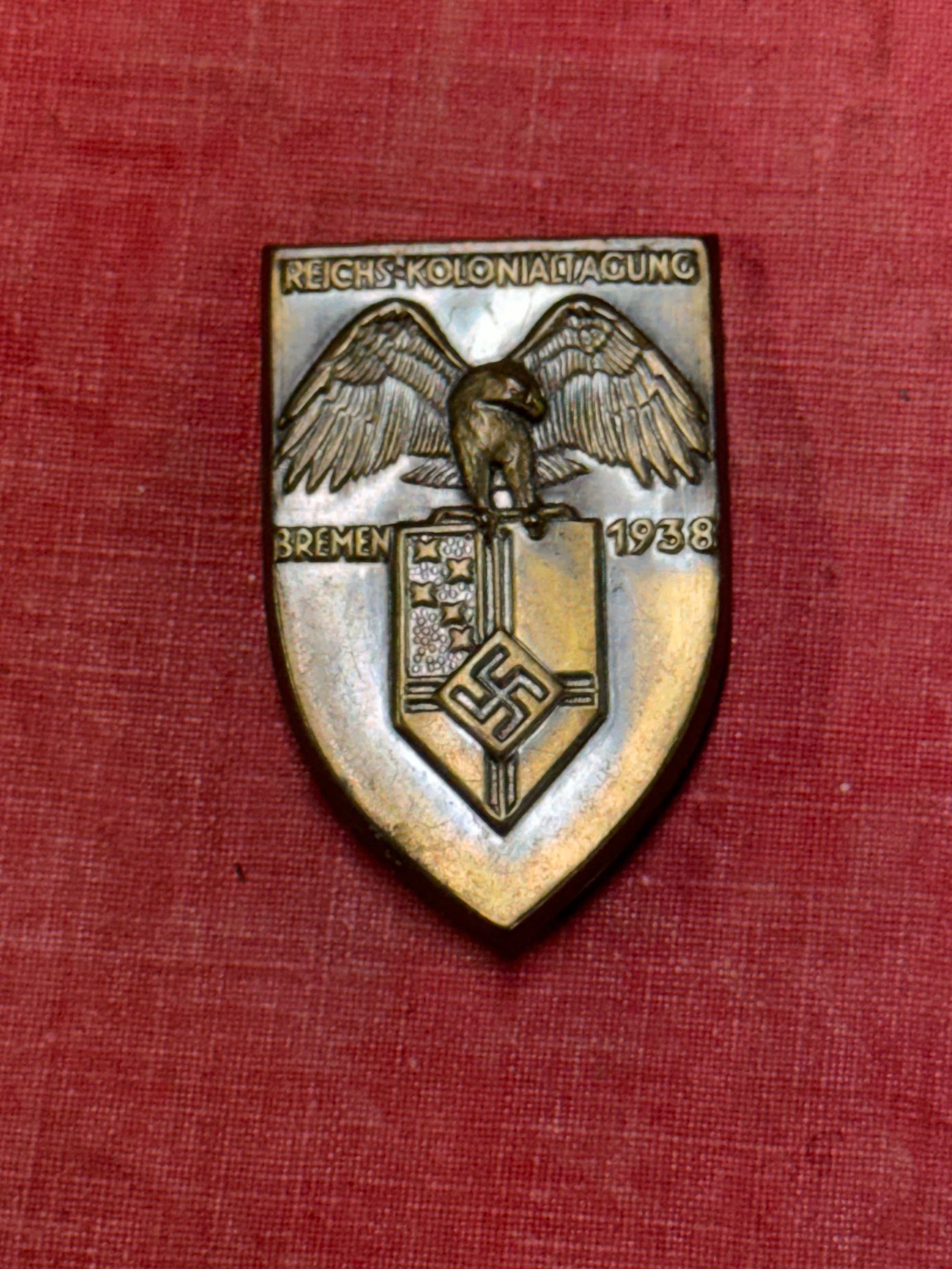 WW2 German Reichskolonialtagung Bremen 1938 Tinnie Badge: WW2 German Reichskolonialtagung Bremen 1938 Tinnie Badge. A rare find. Shows good wear and use with a beautiful overall patina. Metal pin back. Please view all detailed pictures.