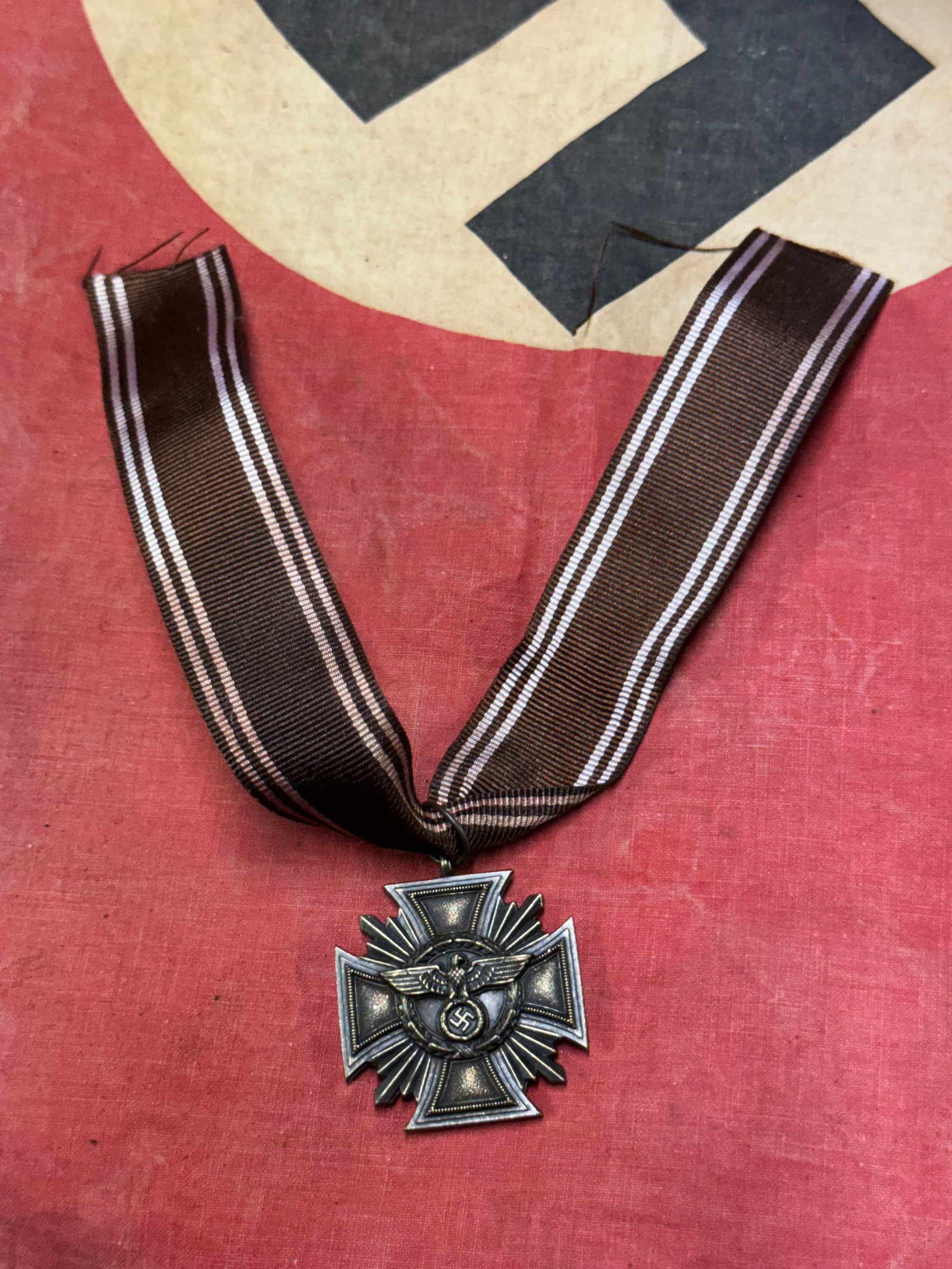 WW2 GERMAN NSDAP 10 YEAR SERVICE MEDAL: WW2 GERMAN NSDAP 10 YEAR SERVICE MEDAL. COMES WITH THE ORIGINAL RIBBON. Two piece zinc construction with integral top loop. Unmarked. Very good condition with majority of the bronze finish intact. Wit