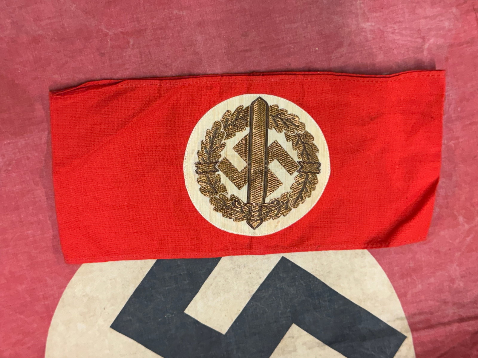 WW2 GERMAN SA SPORTS ARMBAND WITH RZM PAPER TAG: WW2 GERMAN SA SPORTS ARMBAND WITH RZM PAPER TAG. A WW2 German SA sports armband, machine embroidered applied with Bevo centre on red cotton, with RZM on the reverse side. The armband depicts a swastik