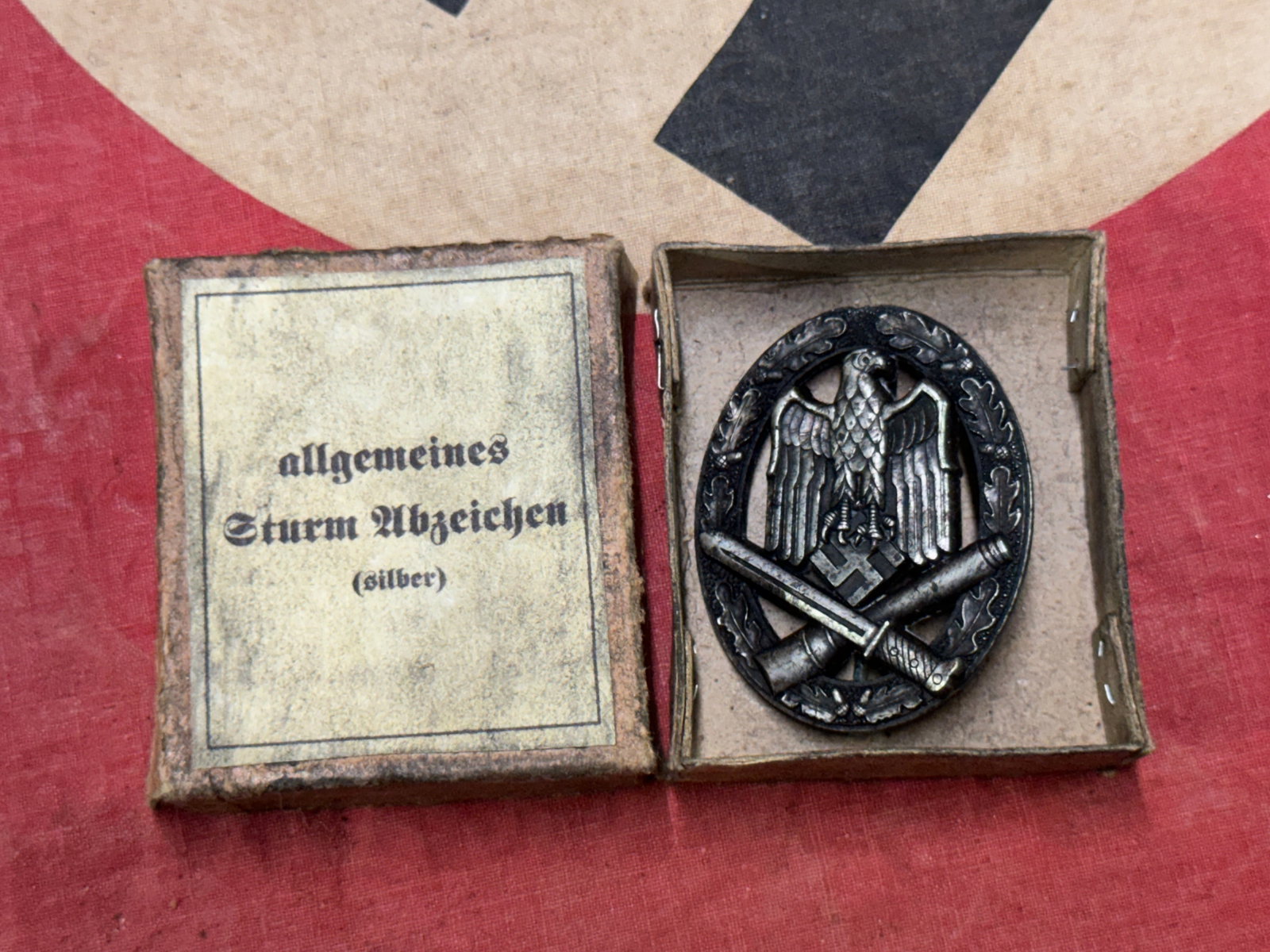 RARE WW2 GERMAN ASSAULT BADGE IN SIVLER IN ORIGINAL BOX: RARE WW2 GERMAN ASSAULT BADGE IN SIVLER IN ORIGINAL BOX. A VERY SCARCE EXAMPLE. SHOWS GOOD WEAR AND USE WITH A BEAUTIFUL OVERALL PATINA. PLEASE VIEW ALL DETAILED PICTURES. MAKER MARKED ON THE REVERSE.