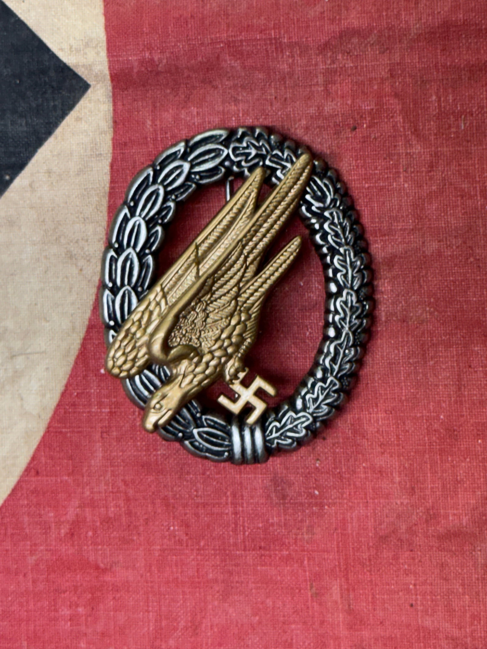 WW2 GERMAN LUFTWAFFE FALLSCHIRMJÄGER BADGE: WW2 GERMAN LUFTWAFFE FALLSCHIRMJÄGER BADGE. An early WW2 German Luftwaffe Fallschirmjäger badge in silvered and gilded tombac with beautiful patina. The obverse consists of a wreath of laurel and oa