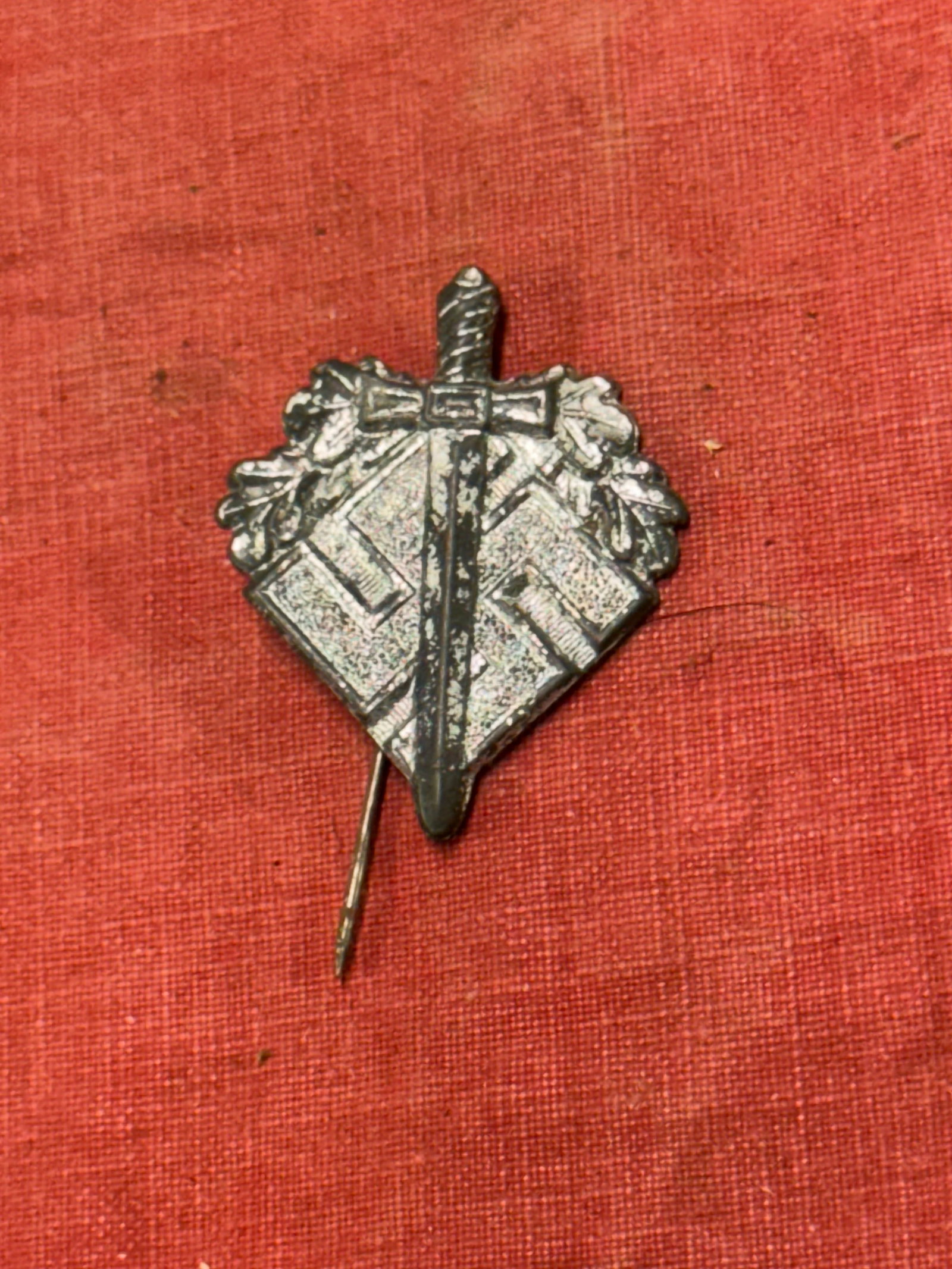 WW2 German NSDAP (NAZI PARTY) N.S.K.O.V. DONATION BADGE: WW2 German NSDAP (NAZI PARTY) N.S.K.O.V. DONATION BADGE. An injection molded aluminum badge with a silver wash, 25mm at its widest point and 32mm tall. It takes the form of a mobile swastika, over whi