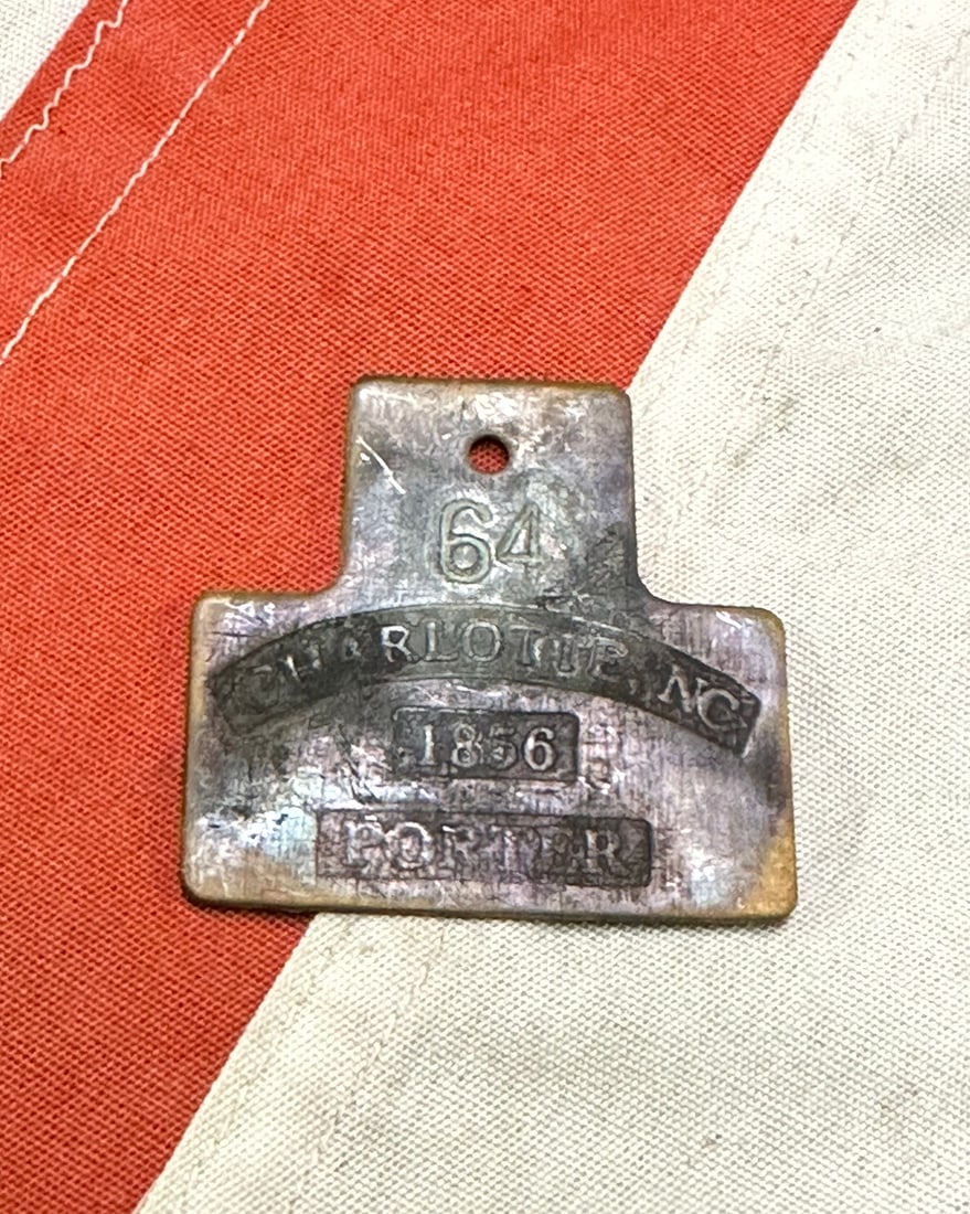 DATED 1856 CHARLOTTE, NC #64 PORTER SLAVE SERVANT ID TAG: DATED 1856 CHARLOTTE, NC #64 PORTER SLAVE SERVANT ID TAG. A RARE FIND. IT IS IN MINT OVERALL SHAPE AND CONDITION WITH A BEAUTIFUL OVERALL PATINA. SHOWS GOOD WEAR AND USE. A VERY RARE FIND.