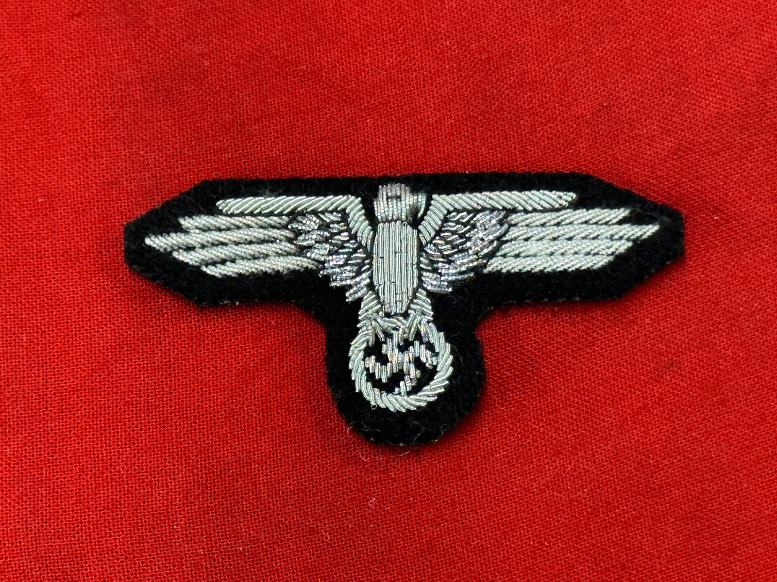 German WWII Army Officers Coat Eagle, Wire Embroidery: German WWII Army Officers Coat Eagle, Wire Embroidery. Silver wire embroidery on dark green wool badge cloth.