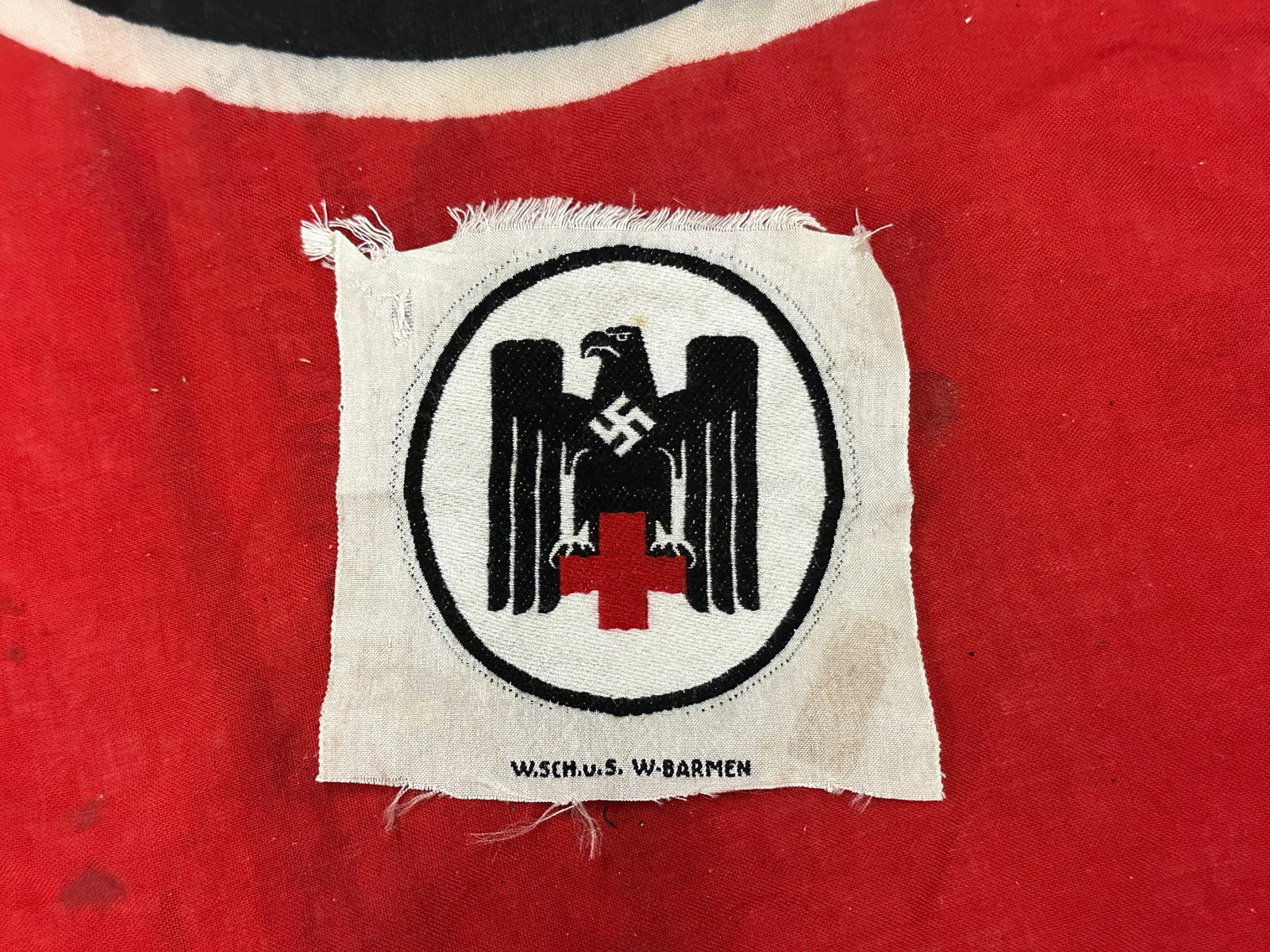 WW2 GERMAN PERIOD DRK (GERMAN RED CROSS) SLEEVE PATCH: A mint and unissued example of a DRK (German Red Cross/Deutsches Rotes Kreuz) sleeve patch; constructed of red, white, and black machine embroidery in the form of a stanard DRK eagle with a mobile swa