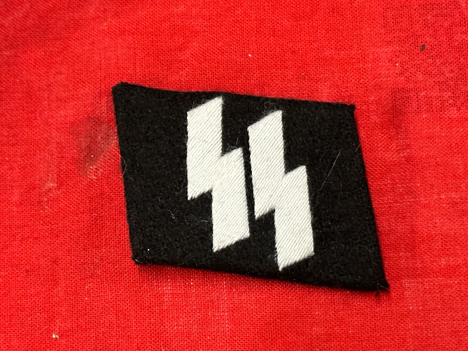 WW2 GERMAN SS UNIFORM COLLAR TAB: WW2 GERMAN SS UNIFORM COLLAR TAB. WW2 GERMAN SS UNIFORM COLLAR TAB. SS TYPE, BEING BULLION SILVER WIRE, ONTO BLACK WOOL BASE. ANGLED FACING BASE, MORE THAN LIKELY FOR FOREIGN VOLUNTEERS UNIFORMS. A RA