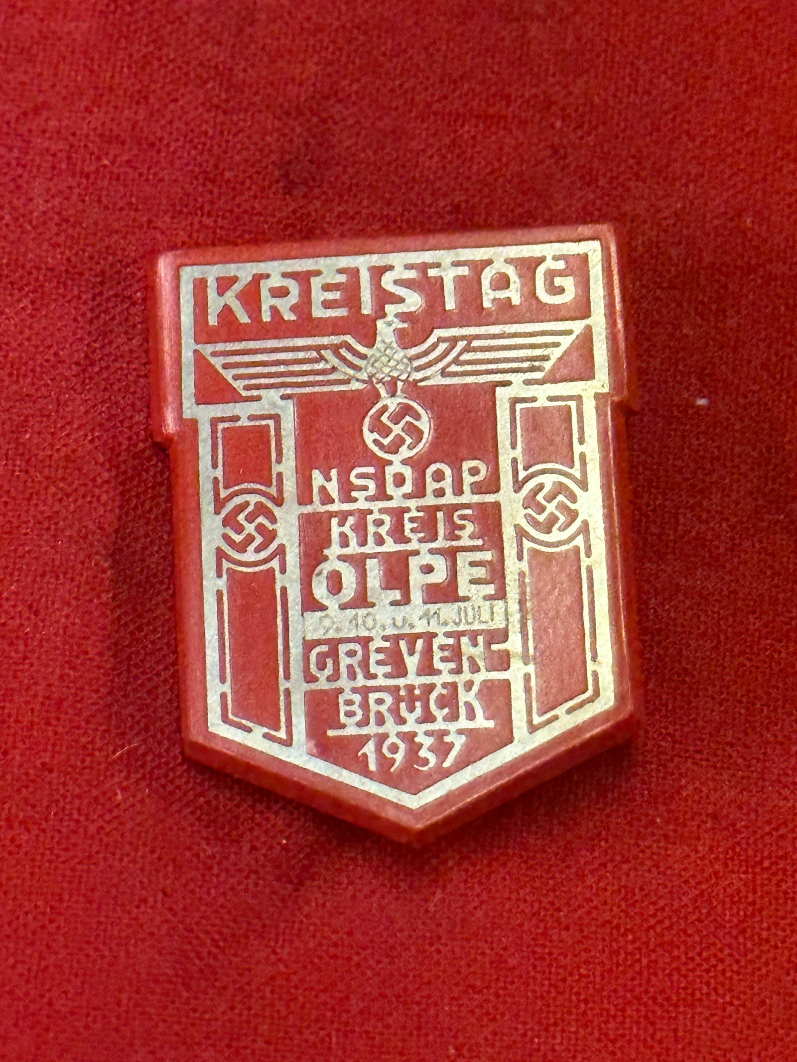 WW2 German NSDPA Kreistag Tinnie Badge In Red: WW2 German NSDPA Kreistag Tinnie Badge In Red. A rare example that is in mint overall shape and condition with a beautiful overall patina. Shows good wear and use. Please view all detailed pictures. A