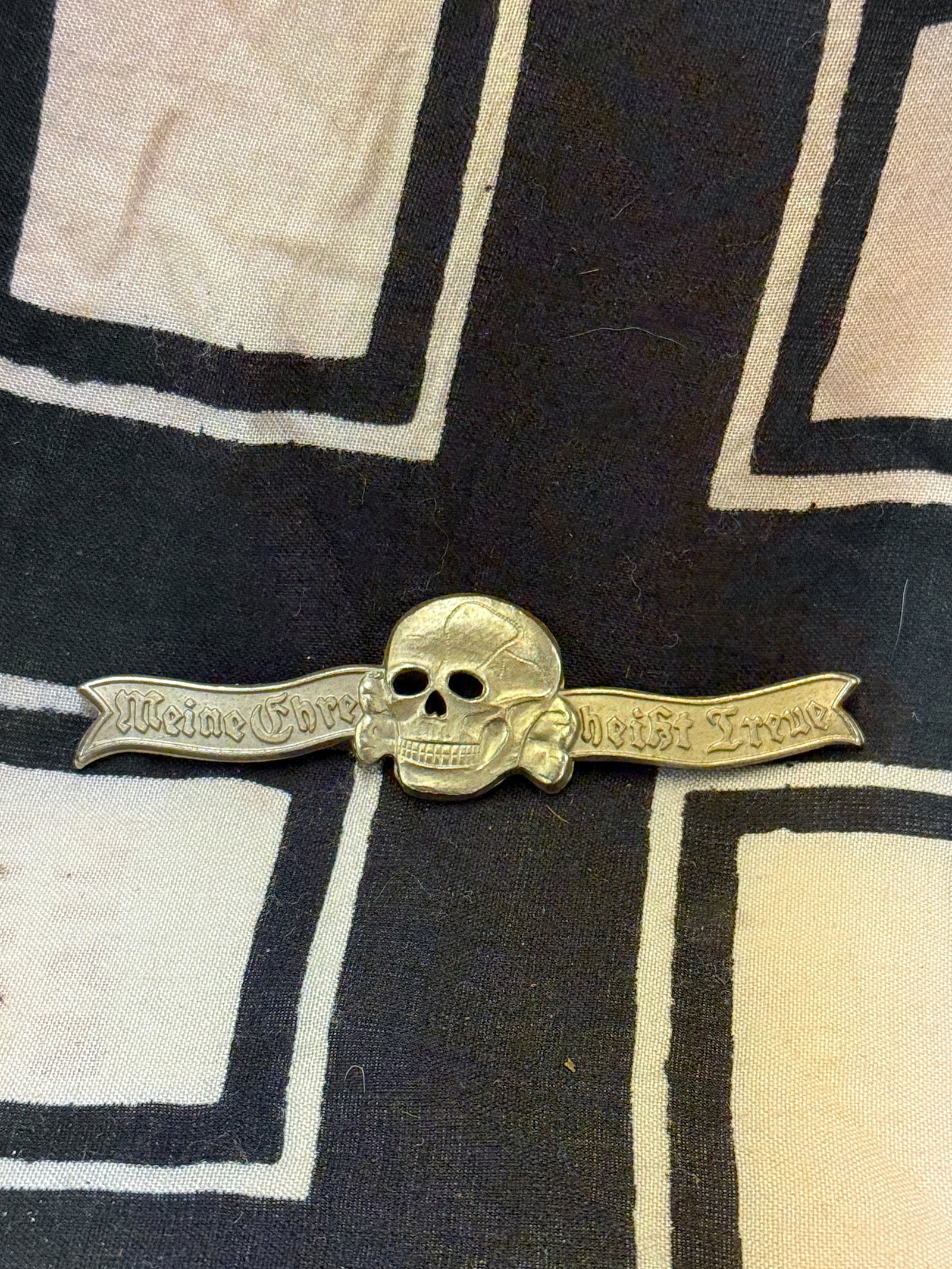 WWII GERMAN SS DINNER JACKET BADGE: WWII GERMAN SS DINNER JACKET BADGE. MISSING THE CLASP ON THE REVERSE. SHOWS GOOD WEAR AND USE WITH A BEAUTIFUL OVERALL PATINA. A NICE DINNER JACKET BADGE WORN BY A TOTENKOPF SS OFFICER. A SCARCE EXAMP