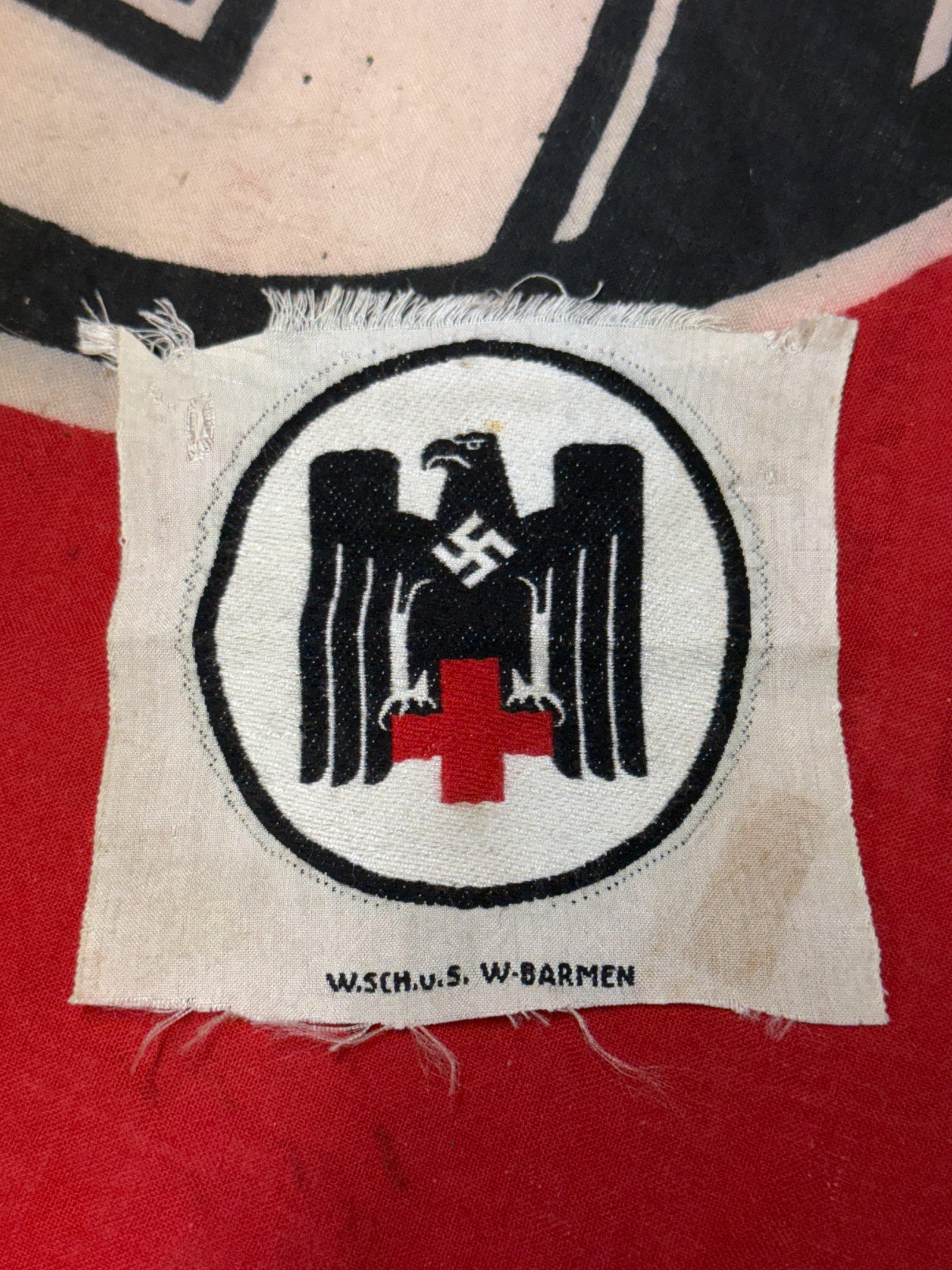Germany. A Mint Second War Period Drk (German Red Cross) Sleeve Patch: A mint and unissued example of a DRK (German Red Cross/Deutsches Rotes Kreuz) sleeve patch; constructed of red, white, and black machine embroidery in the form of a stanard DRK eagle with a mobile swa