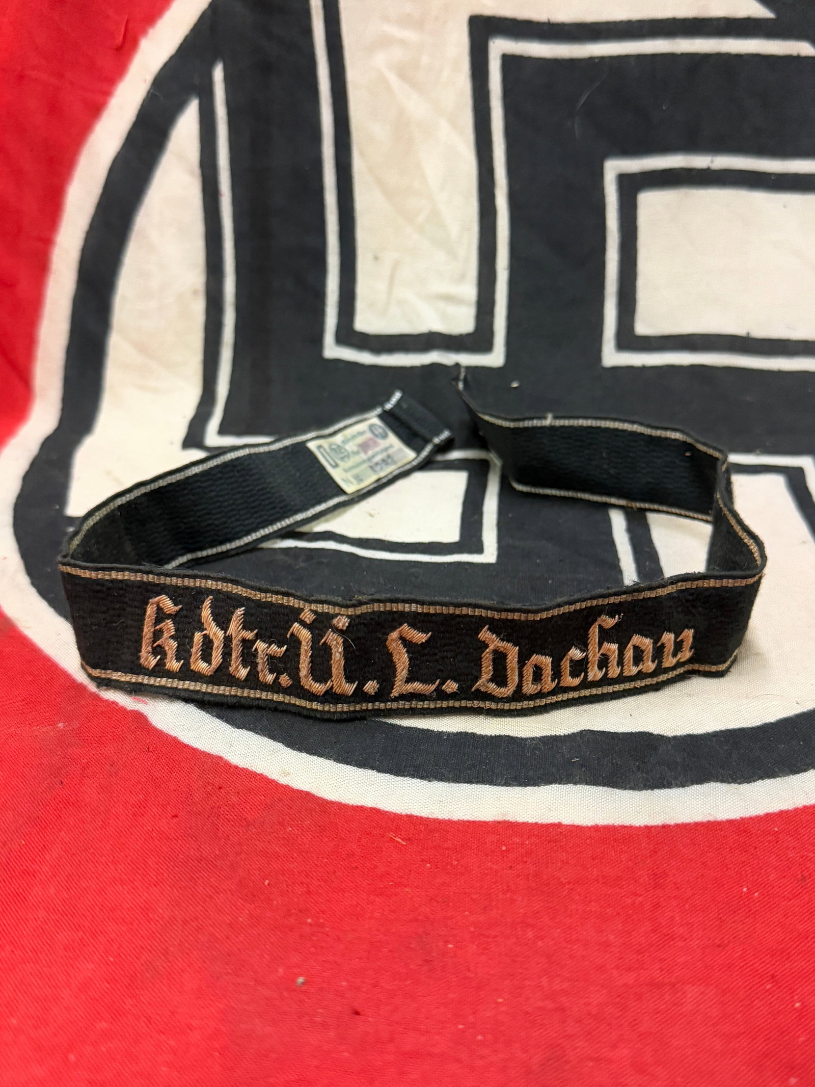 WW2 German Kdre.U.L.Dachau Brassard, Waffen SS Cuff Title With RZM Paper Tag: WW2 German Kdre.U.L.Dachau Brassard, Waffen SS Cuff Title With RZM Paper Tag. A very rare find, showing good wear and use with a beautiful overall patina. Has the RZM maker mark tag still attached to 