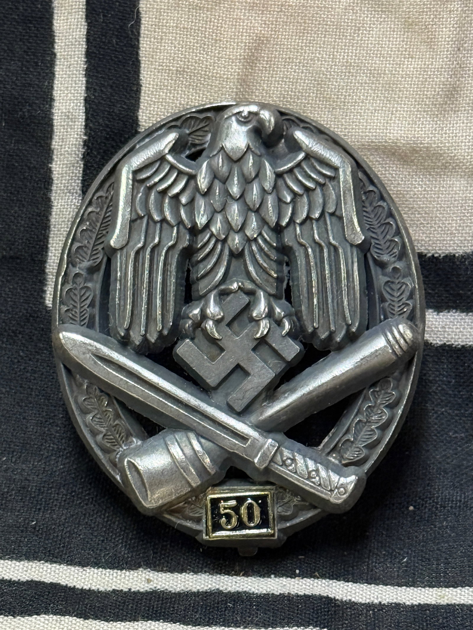 SCARCE WW2 GERMAN GENERAL ASSAULT BADGE FOR 50 ENGAGEMENTS BY JFS: SCARCE WW2 GERMAN GENERAL ASSAULT BADGE FOR 50 ENGAGEMENTS BY JFS. AN ULTRA RARE FIND SHOWING GOOD WEAR AND USE WITH A BEAUTIFUL OVERALL PATINA. MAKER MARKED JFS ON THE REVERSE. PLEASE VIEW ALL DETAIL