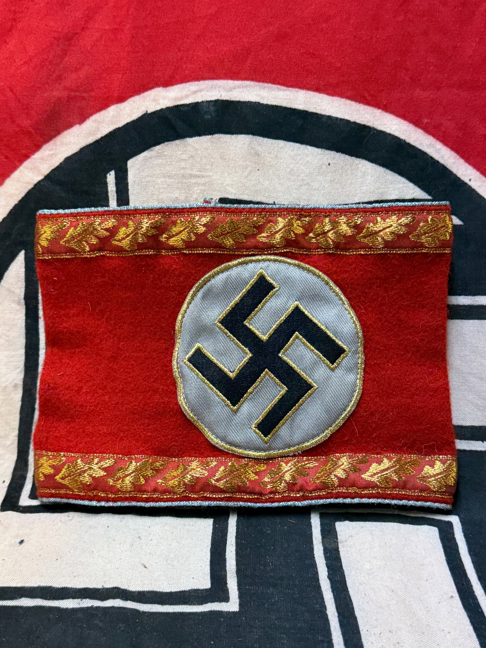 WW2 German Third Reich NSDAP Gauleitung Armband (administrative Department Head): WW2 German Third Reich NSDAP Gauleitung Armband (administrative Department Head). Red wool armband with blue piping to edges, thin row of embroidered golden oak leaves within bands to either side, cen