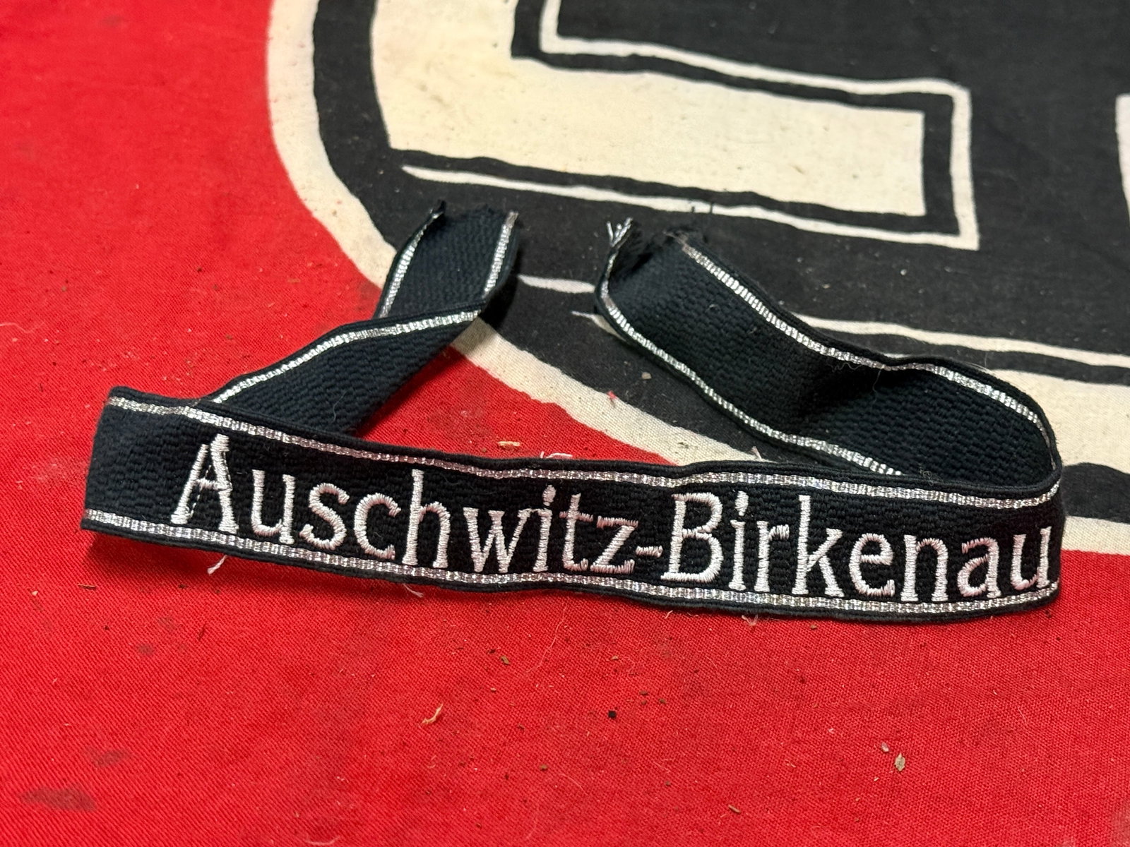 WW2 German Waffen SS Auschwitz - Birkenau Concentration Camp Cuff Title: WW2 German Waffen SS Auschwitz - Birkenau Concentration Camp Cuff Title. Embroidered with correct 7 strand bullion band strips. Shows good wear and use with a beautiful overall patina. Please view all