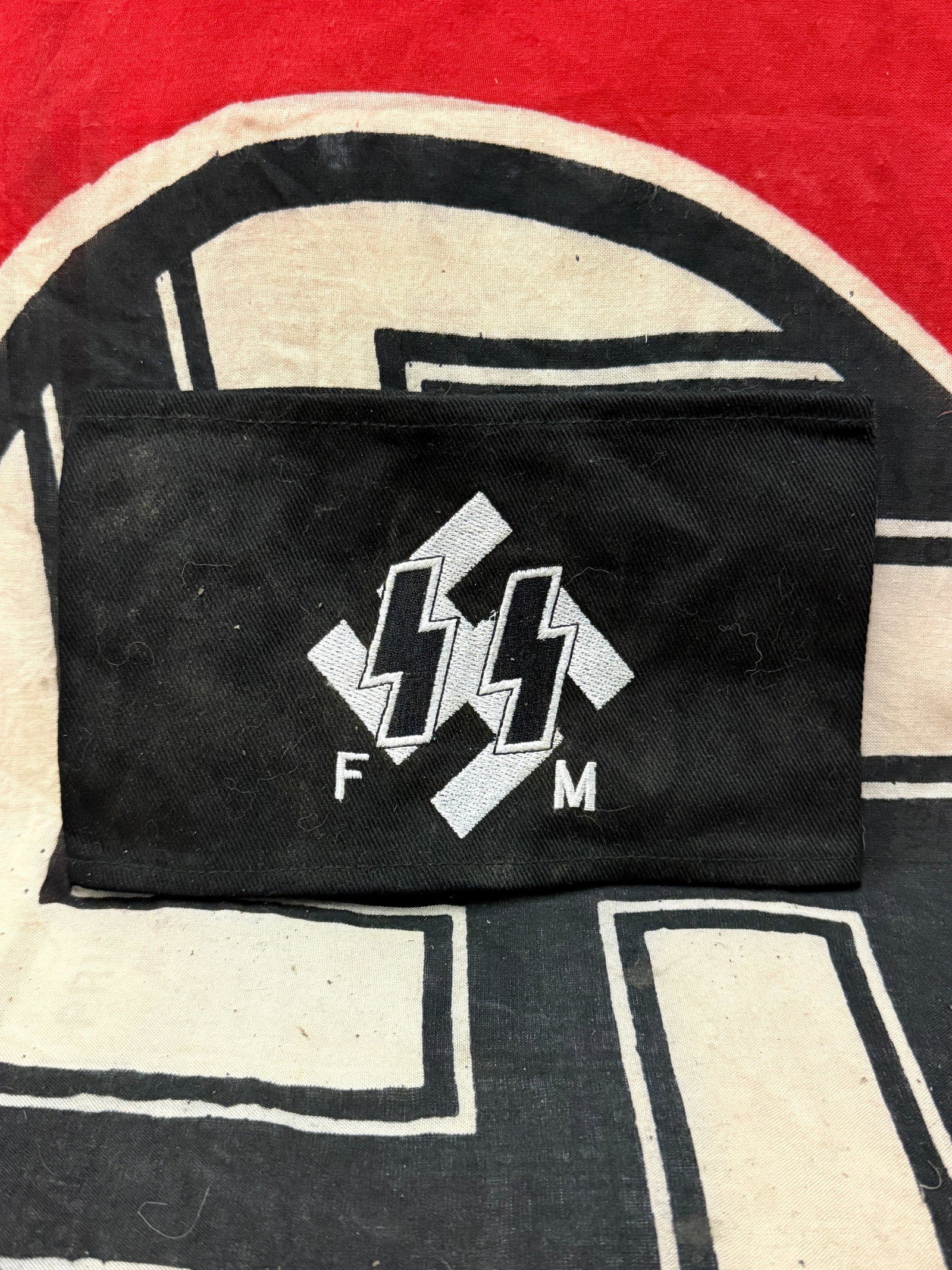 WW2 GERMAN SS FM HONORARY MEMBERS ARMBAND WITH RZM PAPER TAG: WW2 GERMAN SS FM HONORARY MEMBERS ARMBAND WITH RZM PAPER TAG. AN ULTRA RARE FIND, SHOWING GOOD WEAR AND USE WITH A BEAUTIFUL OVERALL PATINA. SS Honorary Members armband, woven on Wool. Comes with the 