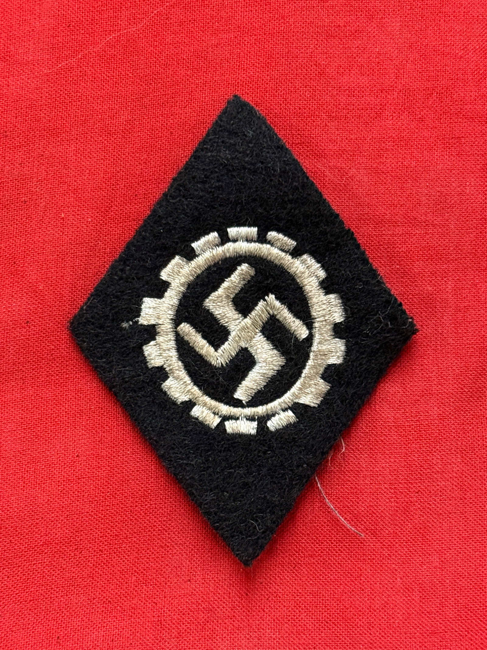 WW2 German DAF Sleeve Diamond: WW2 German DAF Sleeve Diamond. Black wool diamond with silver aluminum cogwheel with swastika. Shows light wear and use with a beautiful patina throughout. Please view all detailed pictures. A scarce 