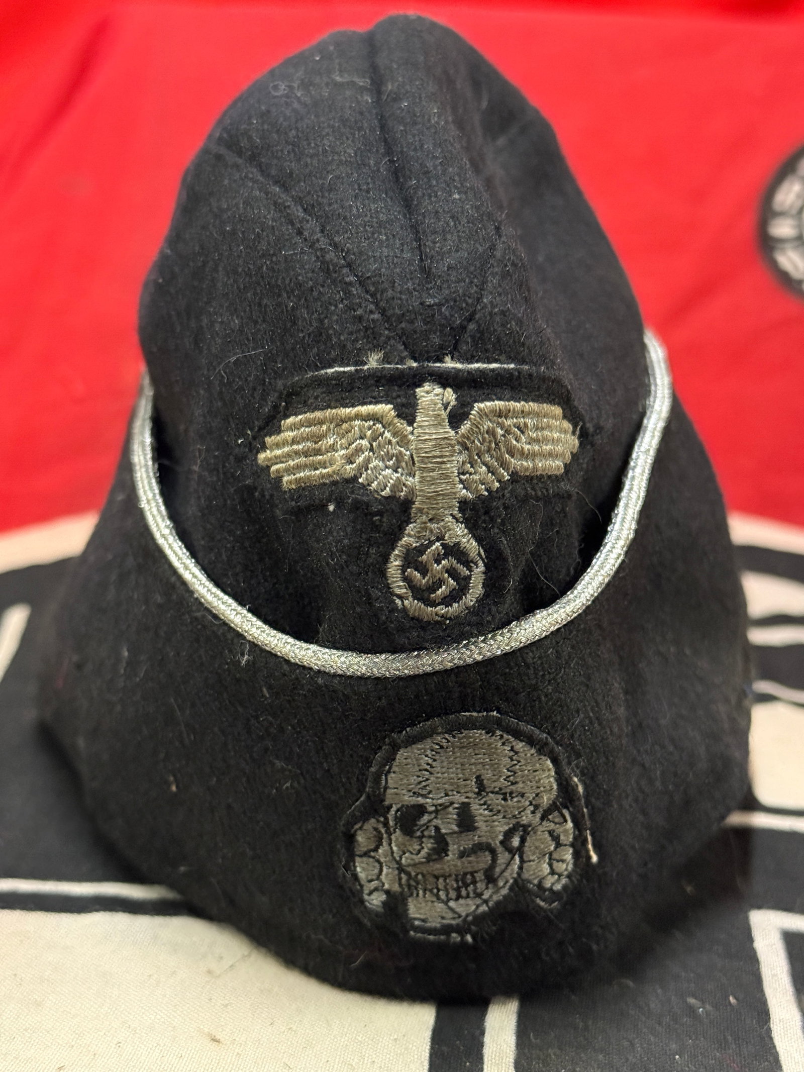 WWII GERMAN THIRD REICH SS PANZER OVERSEA CAP - MAKER MARKED: WWII GERMAN THIRD REICH SS PANZER OVERSEA CAP - MAKER MARKED. German WWII Waffen SS Panzer Officers Overseas Cap. The body is a black wool with silver bullion wire piping. There is a flat wire Waffen 