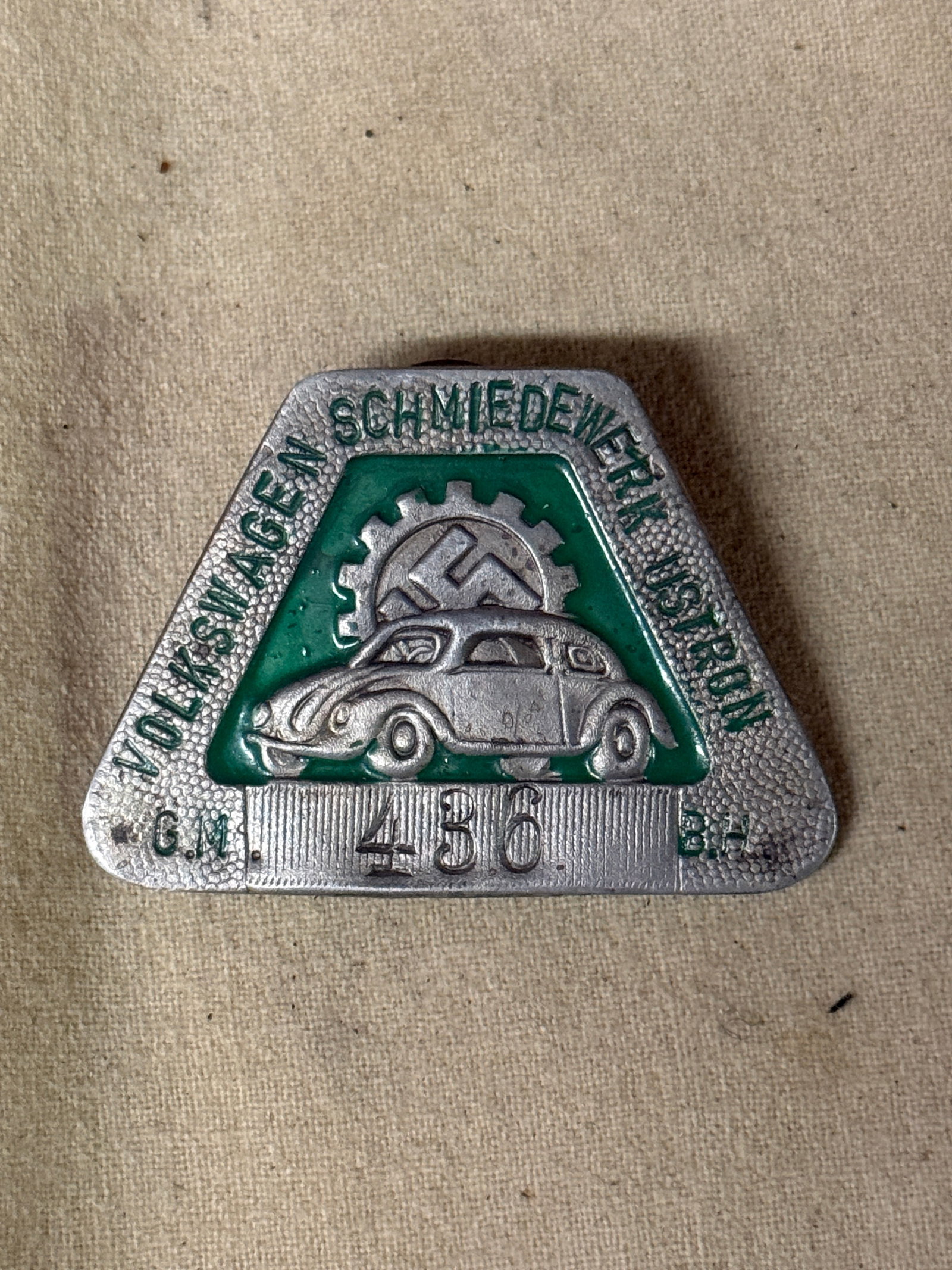 GERMAN WWII ERA VOLKSWAGEN FACTORY EMPLOYEE BADGE: German WWII era Volkswagen factory employee badge featuring a car image with a swastika behind and a number stamped below. Nazi German WWII Era Third Reich Factory Employee Badges For Collectors.