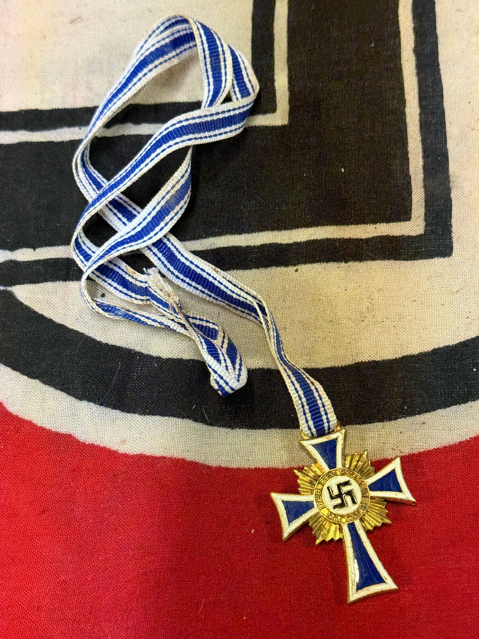 WW2 German Mother’s Cross WITH FULL LENGTH LONG RIBBON Ehrenkreuz der Deutschen Mutter In Bronze: WW2 German Mother’s Cross WITH FULL LENGTH LONG RIBBON Ehrenkreuz der Deutschen Mutter In Bronze. The Mother’s Cross was introduced by Adolf Hitler on December 16TH 1938 as part of a large propaga