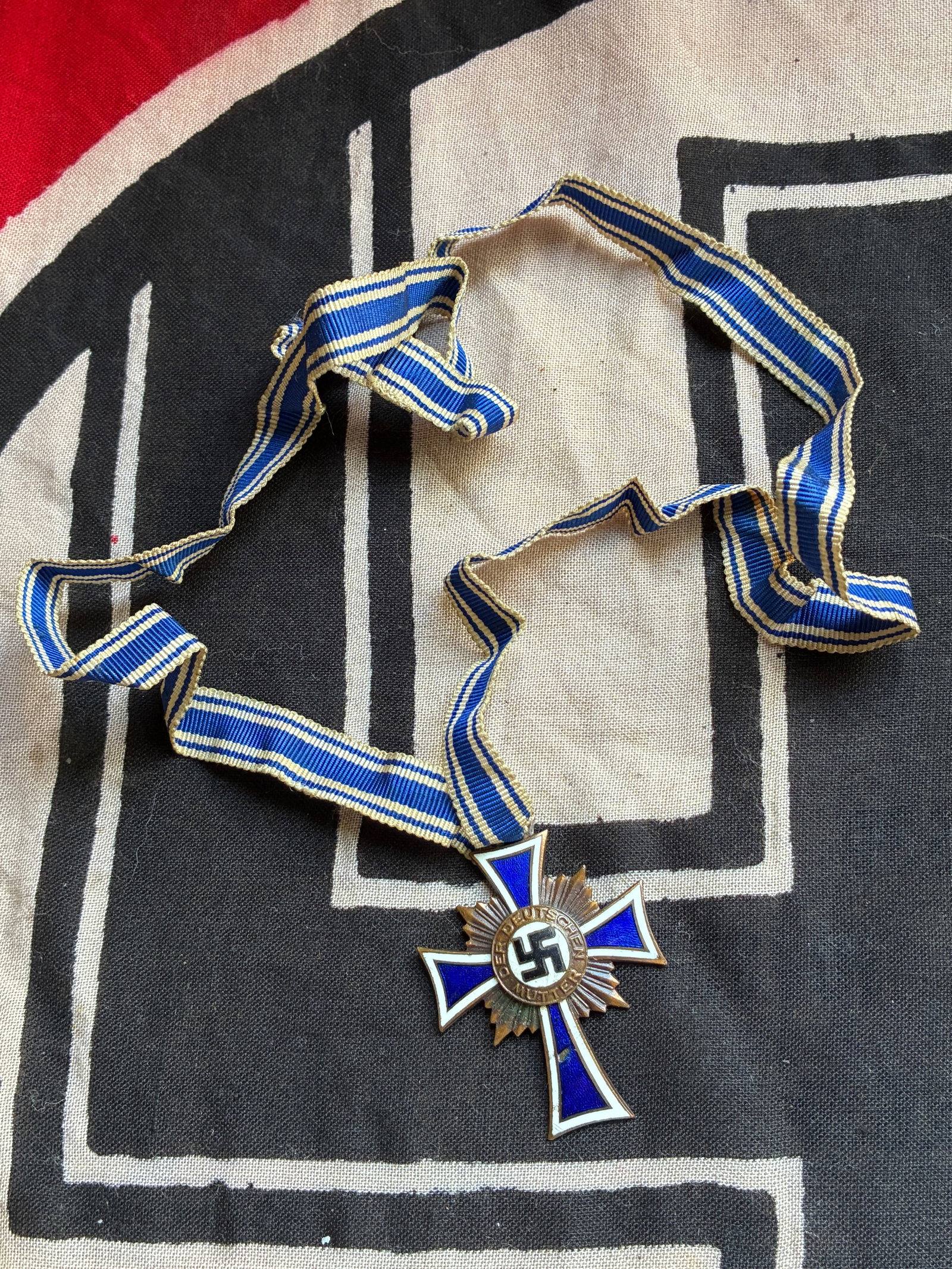 RARE WW2 GERMAN BRONZE MOTHERS CROSS WITH LONG RIBBON: RARE WW2 GERMAN BRONZE MOTHERS CROSS WITH LONG RIBBON. A VERY RARE EXAMPLE. NEAR MINT CONDITION. The Nazi plans for the expansion of the German Reich required a robust and growing German population. T