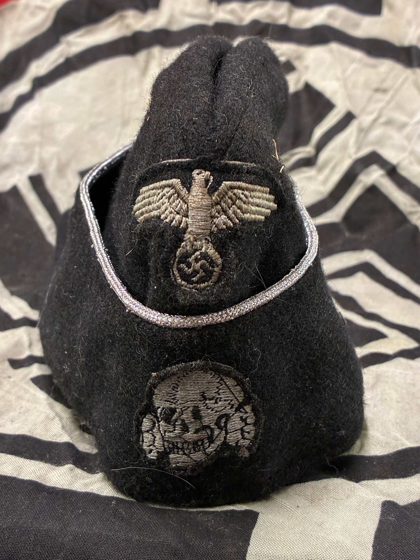 WWII GERMAN THIRD REICH SS PANZER OVERSEAS CAP DATED 1942: WWII GERMAN THIRD REICH SS PANZER OVERSEAS CAP DATED 1942. German WWII Waffen SS Panzer Officers Overseas Cap. The body is a black wool with silver bullion wire piping. There is a flat wire Waffen SS