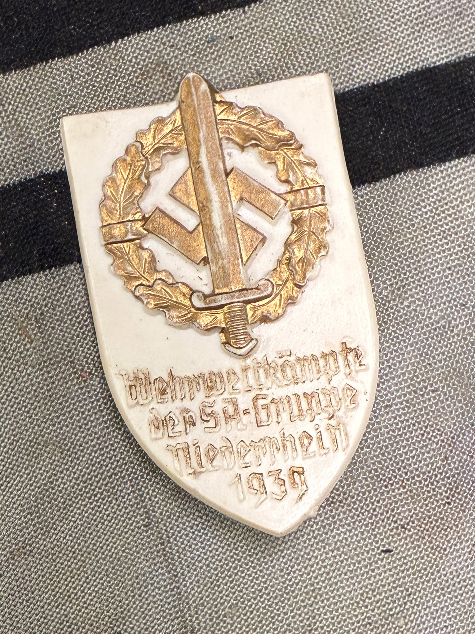 WW2 German Wehrwettkämpfe der SA-Gruppe Niederrhein 1939 Tinnie: WW2 German Wehrwettkämpfe der SA-Gruppe Niederrhein 1939 Tinnie. Shows good wear and use with a beautiful overall patina. Please view all detailed pictures. A scarce example of the time period.