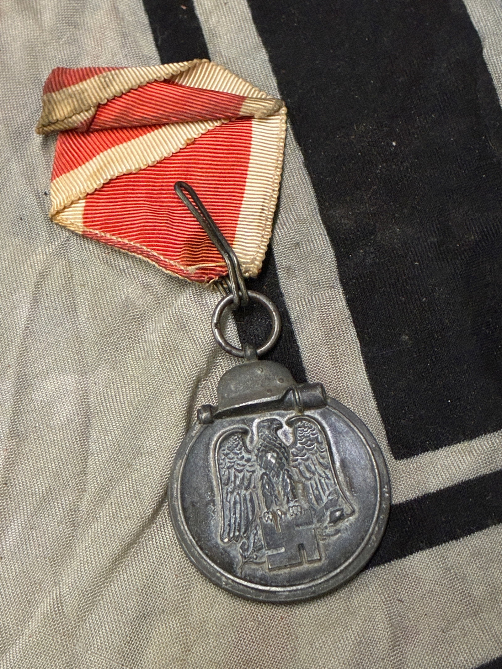 VET BRING BACK WWII GERMAN EASTERN FRONT MEDAL WITH RIBBON: VET BRING BACK WWII GERMAN EASTERN FRONT MEDAL WITH RIBBON. AN ULTRA RARE EXAMPLE THAT IS IN MINT OVERALL SHAPE AND CONDITION WITH A BEAUTIFUL OVERALL PATINA. PLEASE VIEW ALL DETAILED PICTURES. A SCAR