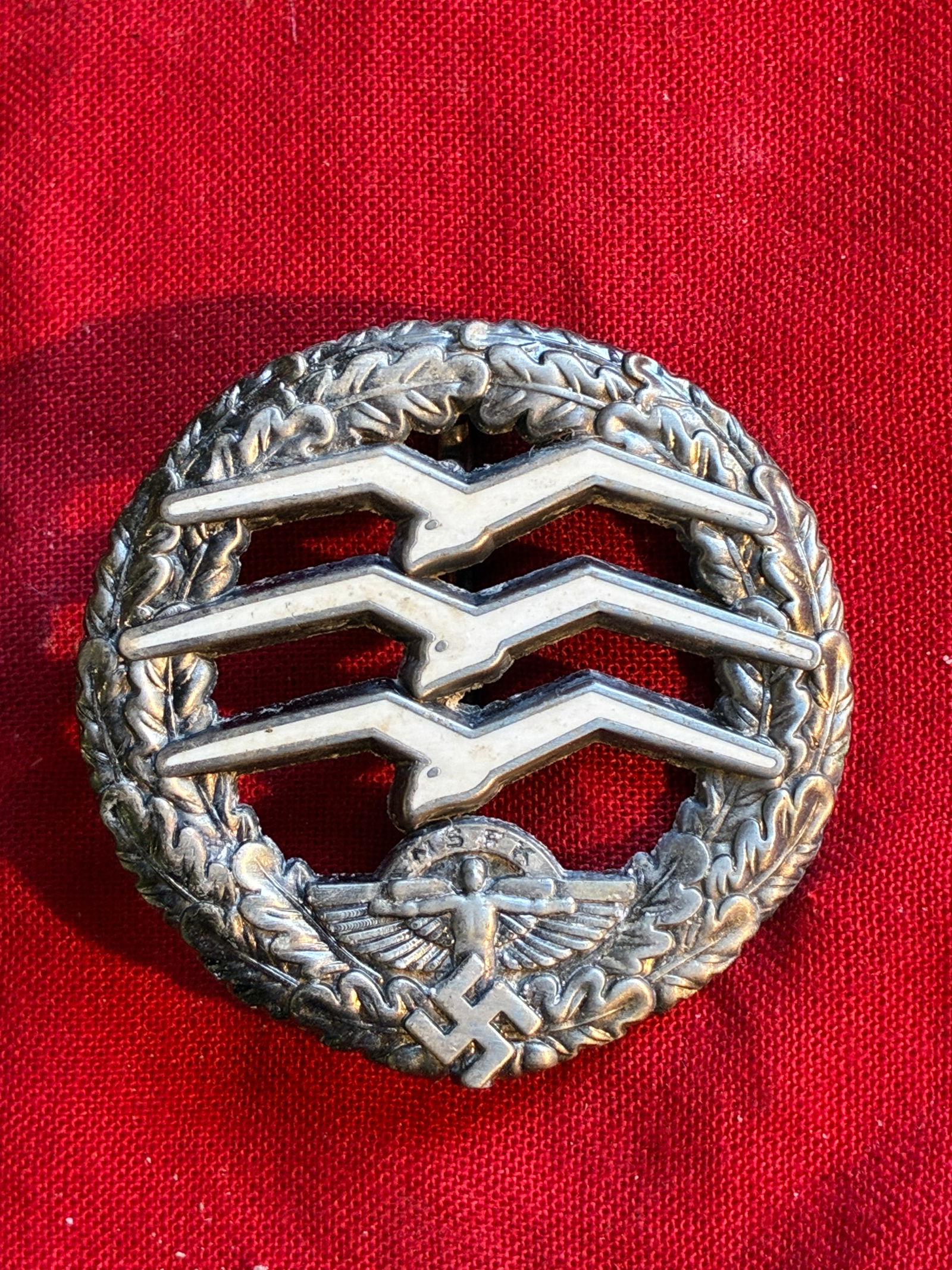 WWII GERMAN THIRD REICH NSFK GLIDER PILOT BADGE: WWII GERMAN THIRD REICH NSFK GLIDER PILOT BADGE. The front shows three gulls in the center surrounded by a round oak leaf wreath. The base shows the Icarus flying man with a swastika at the base.