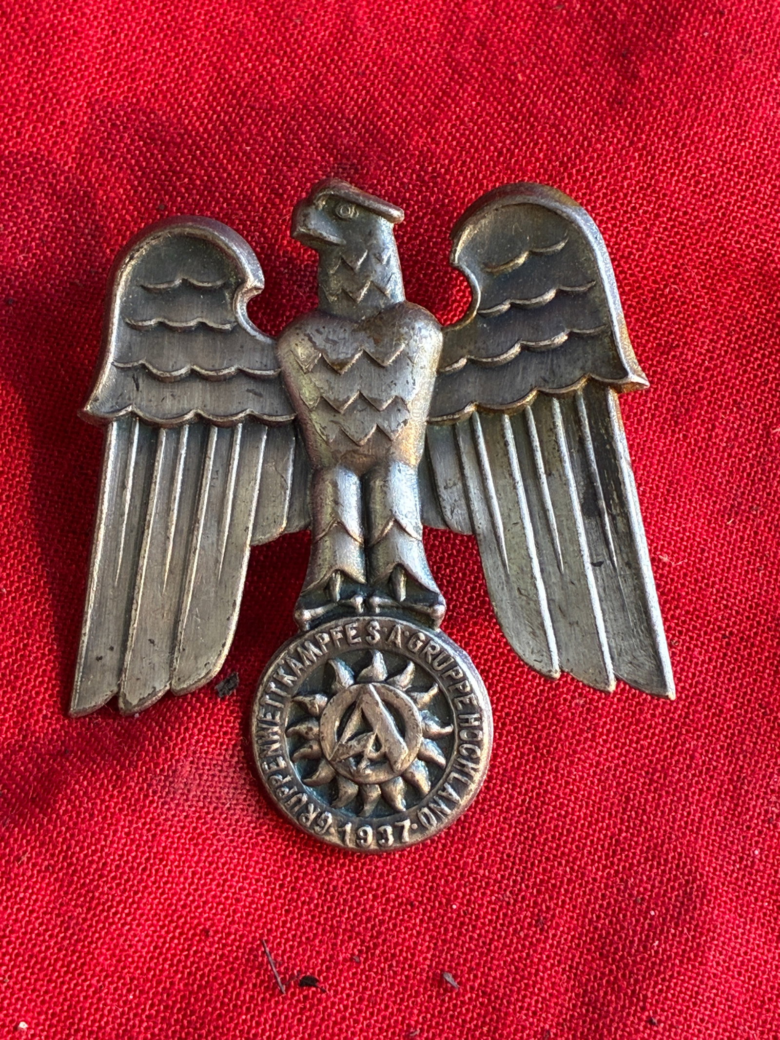 WW2 German NSDAP (NAZI PARTY) S.A. Brownshirts 1937 GRUPPE HOCHLAND DAY BADGE: WW2 German NSDAP (NAZI PARTY) S.A. Brownshirts 1937 GRUPPE HOCHLAND DAY BADGE. The badge is in the form of an eagle clutching a circular disk. The disk has the SA insignia superimposed on the sun, sur