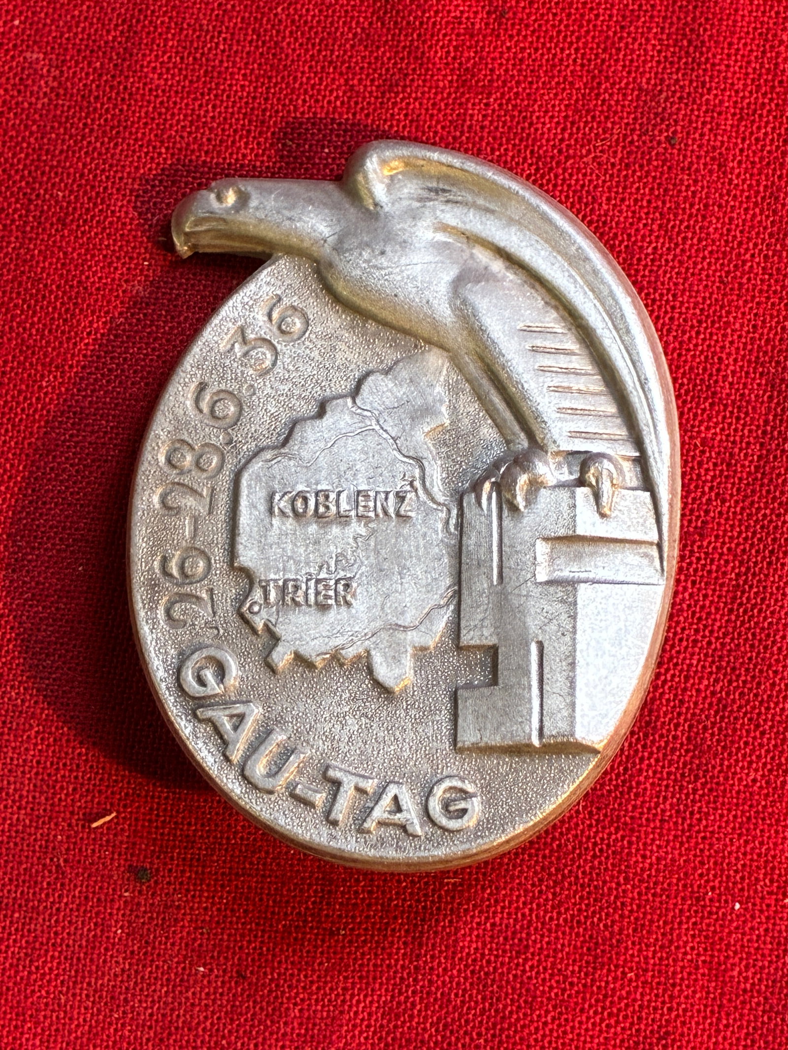 WW2 German NSDAP (NAZI PARTY) 1936 KOBLENZ-TRIER PROVINCIAL DAY BADGE: WW2 German NSDAP (NAZI PARTY) 1936 KOBLENZ-TRIER PROVINCIAL DAY BADGE. Stamped aluminum badge, roughly in the form of a vertical oval. The west German province of Moselland is to the center of the bad