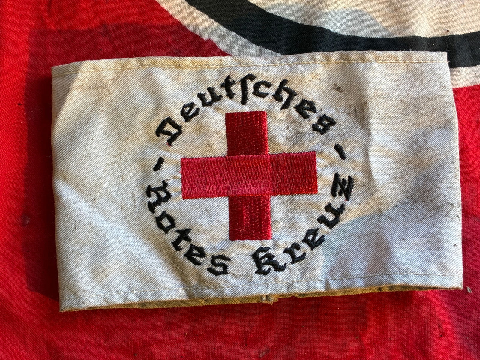 WW2 German DRK Red Cross Member’s Armband: WW2 German DRK Red Cross Member’s Armband. (Deutsches Rotes Kreuz Armband für Mitglieder). Constructed of white cotton, the exterior with a central machine-embroidered red Geneva Cross, circumscrib