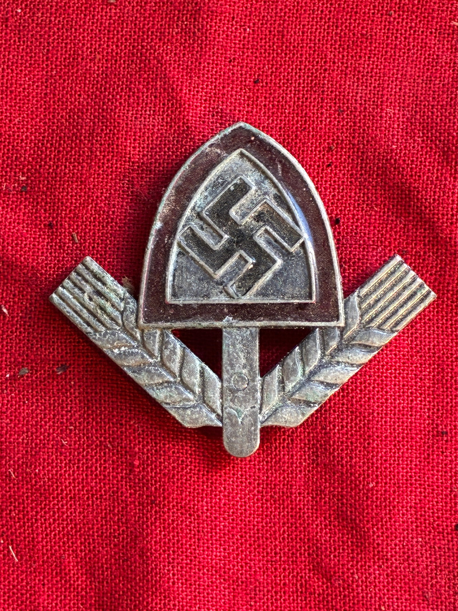 WW2 German Maker-Marked Wartime RAD (Reichsarbeitsdienst/Reich Labour Service) Hat Badge: WW2 German Maker-Marked Wartime RAD (Reichsarbeitsdienst/Reich Labour Service) Hat Badge. The badge displays a swastika at center flanked by stalks of wheat. Makaer marked Ges. Gesch. B&N.