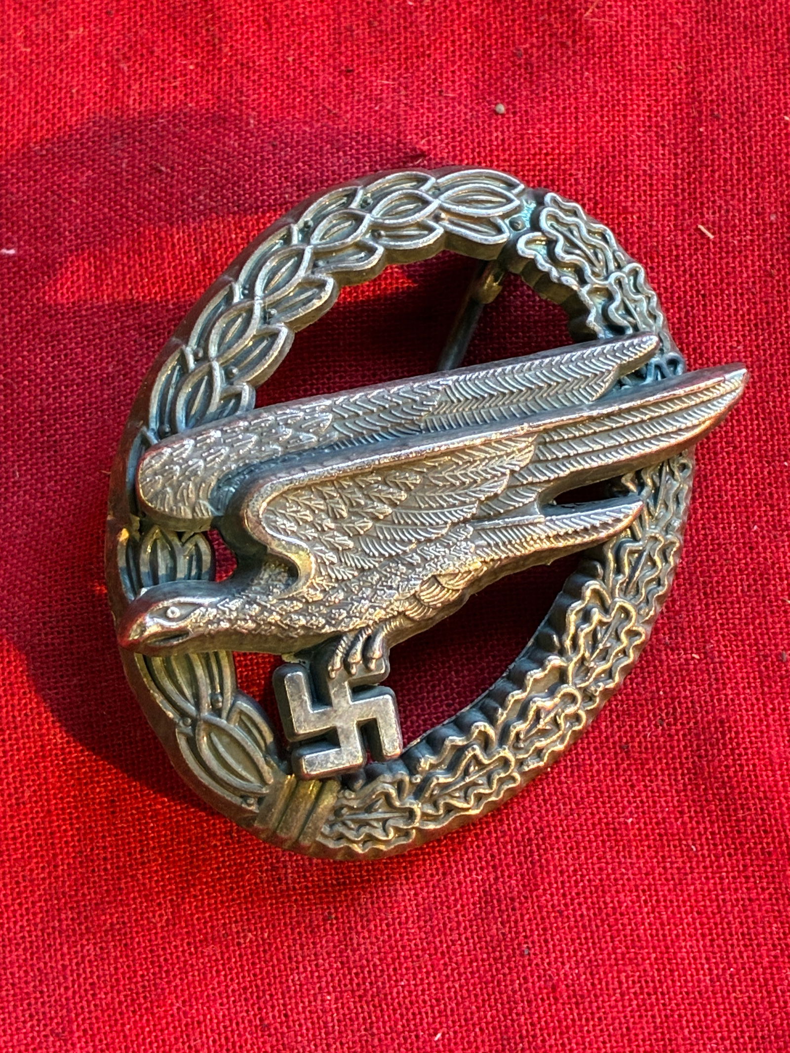 WWII GERMAN THIRD REICH PARATROOPER BADGE BY B&NL: German WWII Luftwaffe Paratrooper Fallschirmjager Jump Badge. The badge shows a diving eagle clutching a swastika in his talons. Both are surrounded by an oval oak leaf wreath. The reverse side is mak