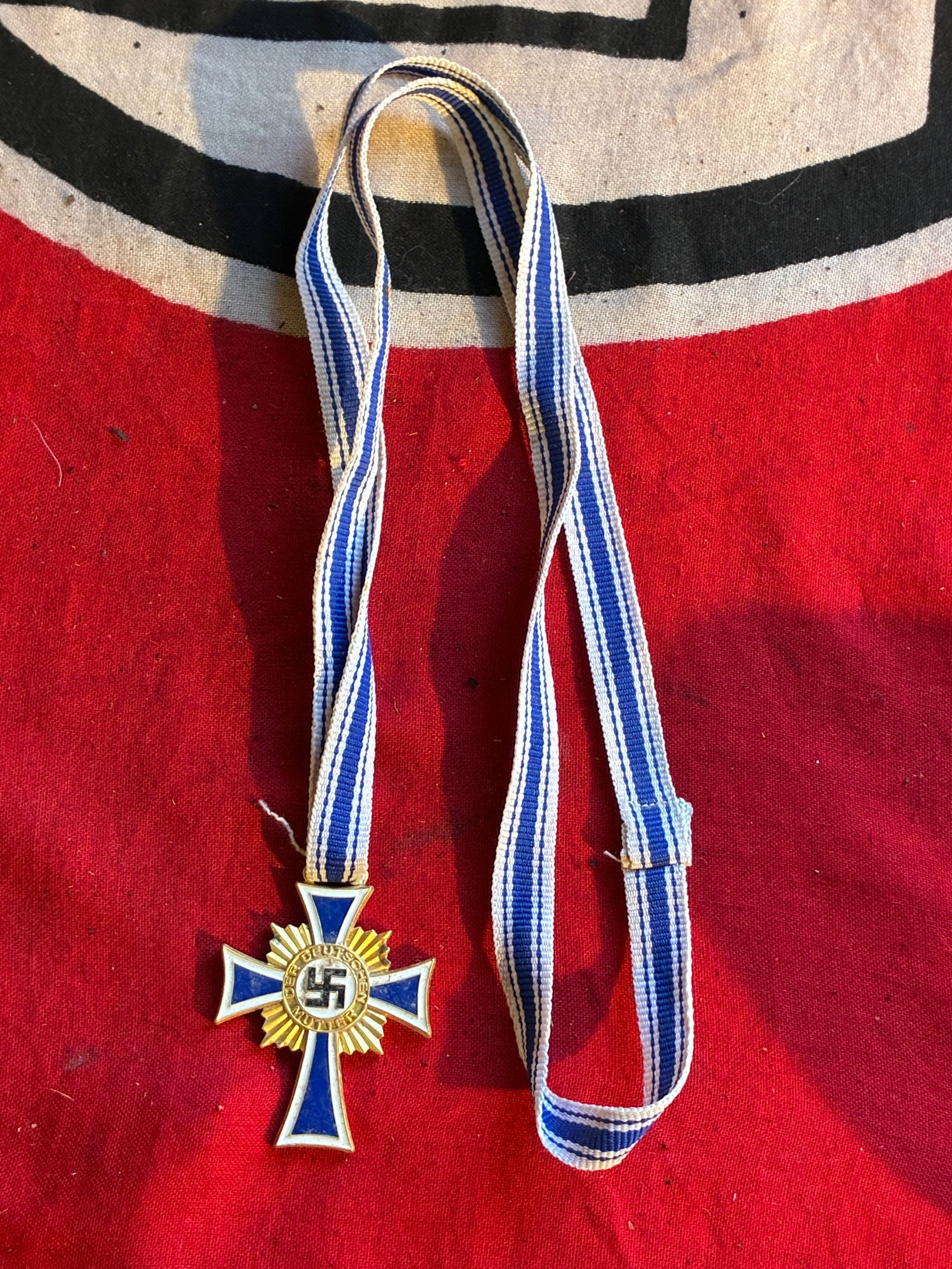 SCARCE WW2 GERMAN MOTHERS CROSS IN GOLD WITH LONG RIBBON: SCARCE WW2 GERMAN MOTHERS CROSS IN GOLD WITH LONG RIBBON. A RARE FIND. SHOWS GOOD WEAR AND USE WITH A BEAUTIFUL OVERALL PATINA. THIS EXAMPLE COMES WITH THE LONG RIBBON. PLEASE VIEW ALL DETAILED PICTUR