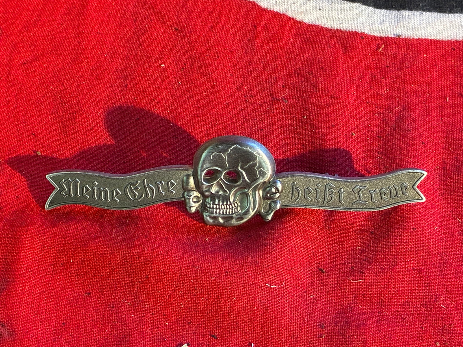 WWII THIRD REICH GERMAN SS OFFICERS DRESS PIN BY RZM M1/34: WWII THIRD REICH GERMAN SS OFFICERS DRESS PIN BY RZM M1/34. Totenkopf at center with motto 'Meine ehre heist Treue' in relief, two posts on reverse, 4 inches long. A RARE EXAMPLE.