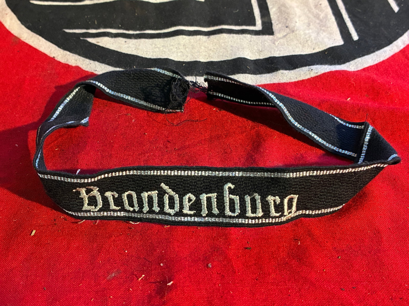 A WW2 German Cufftitle for Officers of SS-TK-Standarte 2 "Brandenburg": A WW2 German Cufftitle for Officers of SS-TK-Standarte 2 "Brandenburg". Black woven band with 7-thread silver-aluminum borders, "Brandenburg" hand-embroidered in silver-aluminum. A very rare example o