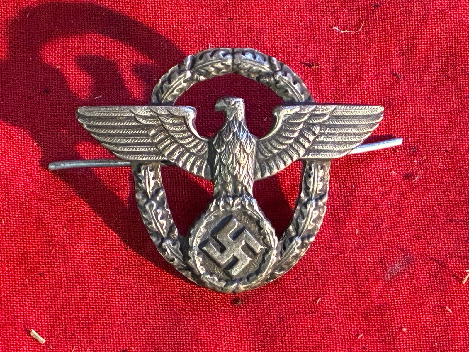 WWII GERMAN POLICE VISOR CAP EAGLE: WWII GERMAN POLICE VISOR CAP EAGLE. RETAINS BOTH MOUNTING PRONGS. SHOWS GOOD WEAR AND USE WITH A BEAUTIFUL OVERALL PATINA. A RARE FIND.
