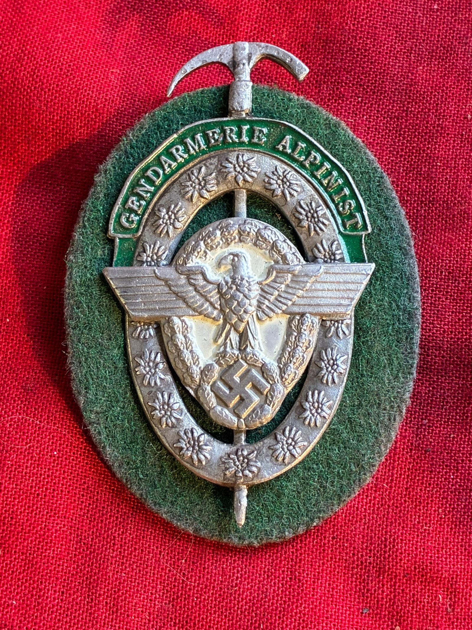 WW2 German 'Gendarmerie Alpinist' Police Award Badge By RZM: WW2 German 'Gendarmerie Alpinist' Police Award Badge By RZM. The award offered is non-fluroescence, metal with some slight wear and manufacturer stamp to reverse, with green wool underlying mounting r