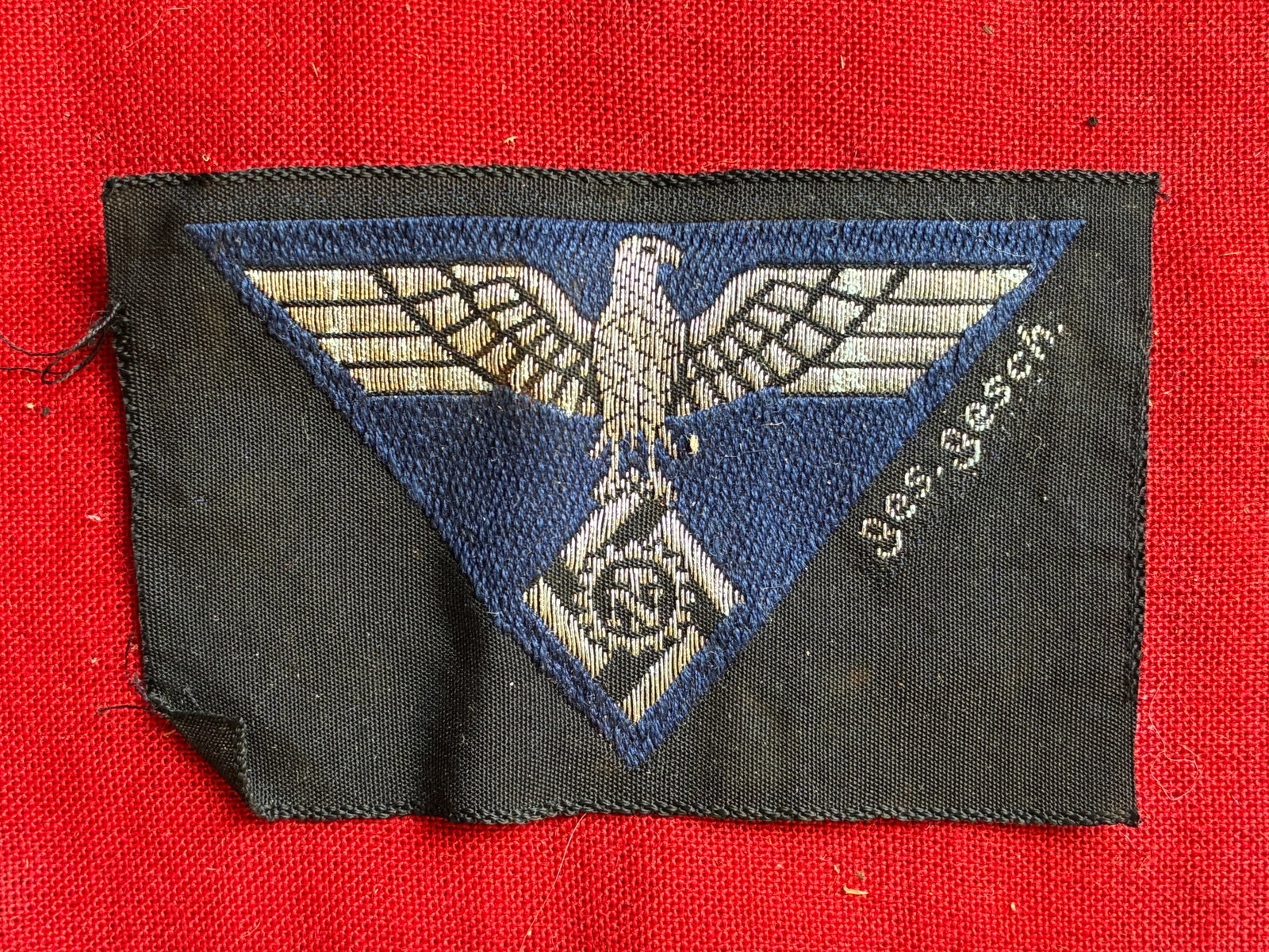 GERMAN WWII TENO ENLISTED MANS OVERSEAS CAP EAGLE: GERMAN WWII TENO ENLISTED MANS OVERSEAS CAP EAGLE. Very finely Bevo woven in silver on blue with ‘Ges Gesch’. Cut from roll.