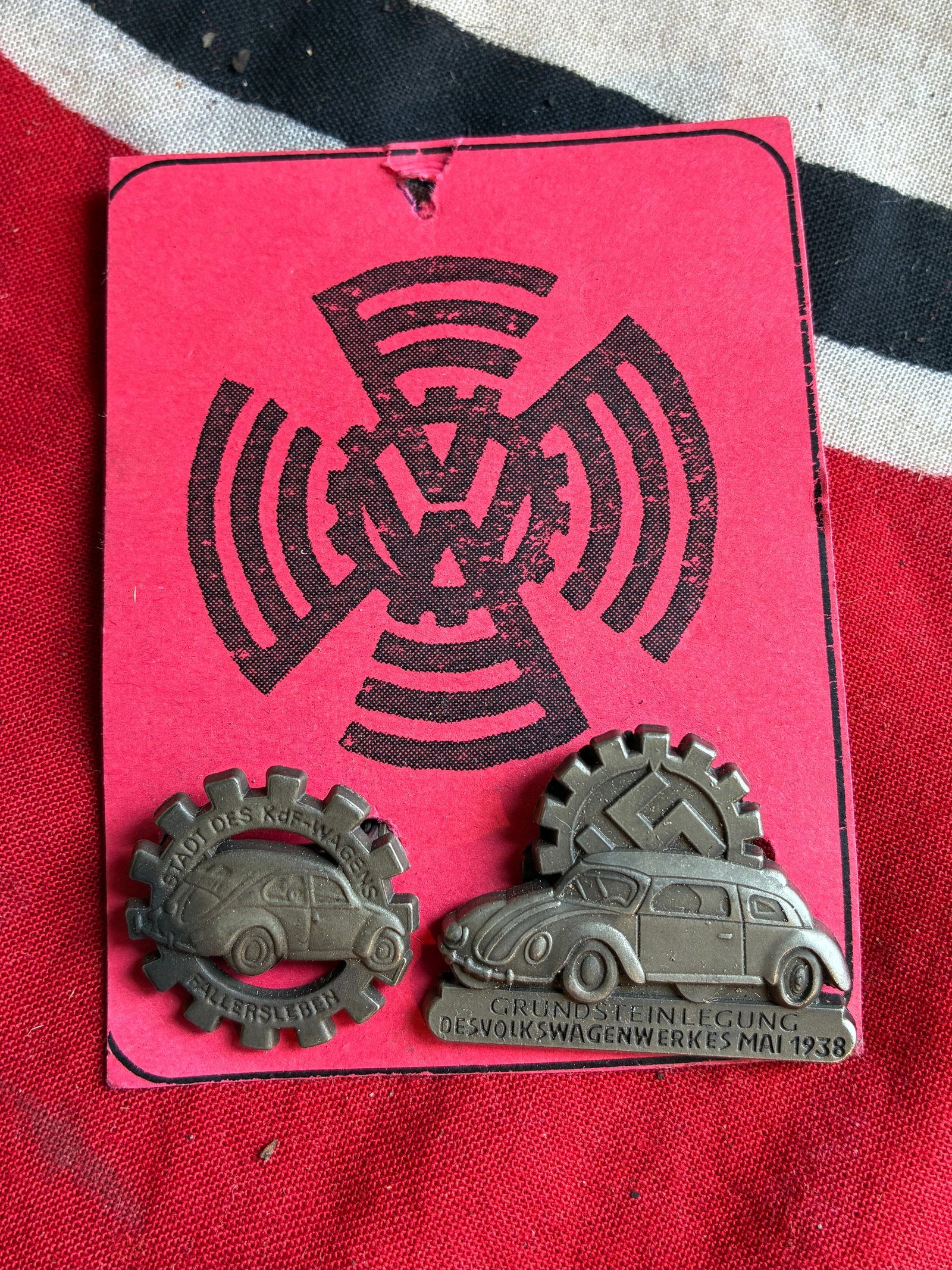 SET OF (2) WW2 GERMAN VOLKSWAGEN FACTORY WORKS TUNIC BADGES ON ORIGINAL PAPER TAG: SET OF (2) WW2 GERMAN VOLKSWAGEN FACTORY WORKS TUNIC BADGES ON ORIGINAL PAPER TAG. AN ULTRA RARE FIND, SHOWING GOOD WEAR AND USE WITH A BEAUTIFUL OVERALL PATINA. PLEASE VIEW ALL DETAILED PICTURES. A R