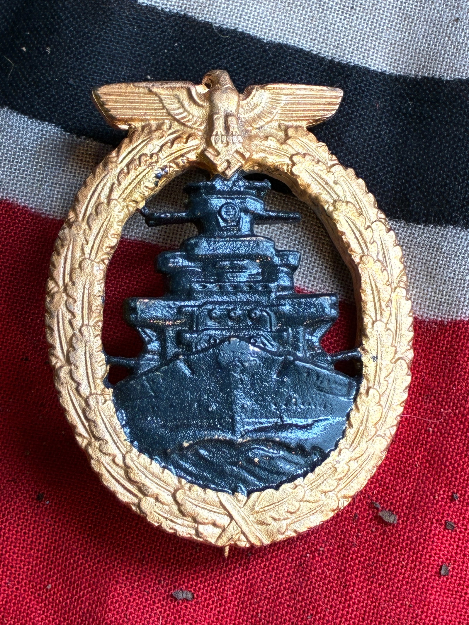 WW2 German Kriegsmarine High Seas Fleet Badge (gilt and grey): WW2 German Kriegsmarine High Seas Fleet Badge (gilt and grey). A grey approaching battleship within a gilt oval oak-leaf wreath surmounted by an eagle and swastika. Please view all detialed pictures.
