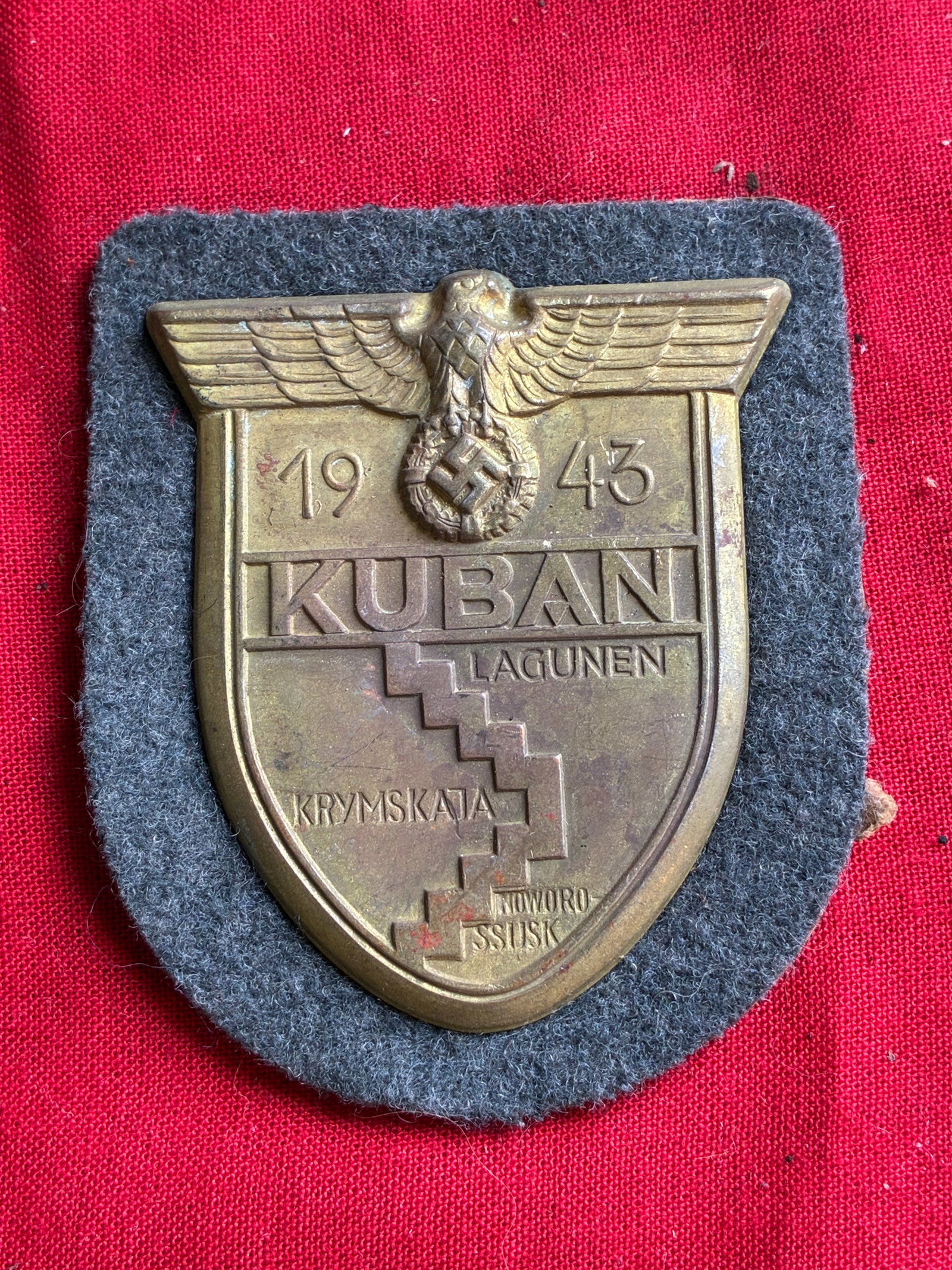 WW2 German Kuban Sleeve Sheild in Zinc Bronzed ON Dark Blue Cloth Backing: WW2 German Kuban Sleeve Sheild in Zinc Bronzed ON Dark Blue Cloth Backing. A very rare find. Shows good wear and use with a beautiful overall patina. Appears to be well worn and use. Please view all d