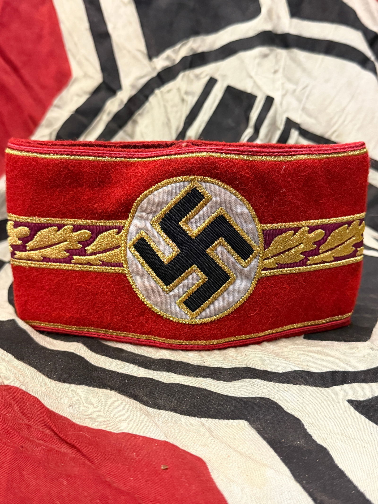 WWII GERMAN THIRD REICH ORTSGRUPPENLEITER ARMBAND WITH RZM PAPER TAG: WWII GERMAN THIRD REICH ORTSGRUPPENLEITER ARMBAND WITH RZM PAPER TAG. Third Reich NSDAP Ortsgruppenleiter armband. Gold bullion oak leaves with bullion trim and single pip on swastika. Multi-piece con