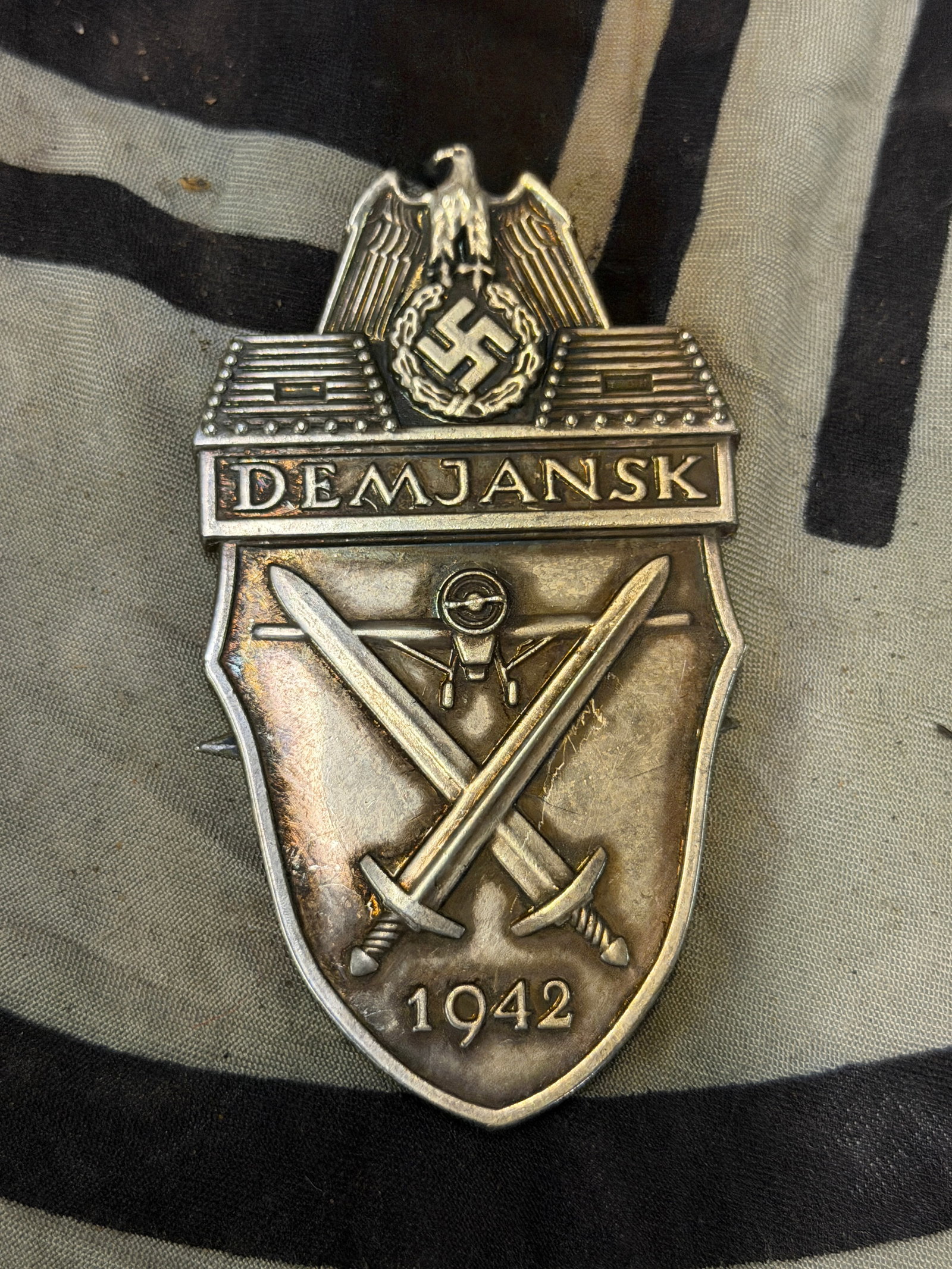 EARLY WW2 GERMAN DEMJANSK SLEEVE SHIELD BADGE: EARLY WW2 GERMAN DEMJANSK SLEEVE SHIELD BADGE. Steel construction with soldered on prongs. Mint condition but with no missing prongs. Fantastic untouched obverse. No backing plate / cloth.