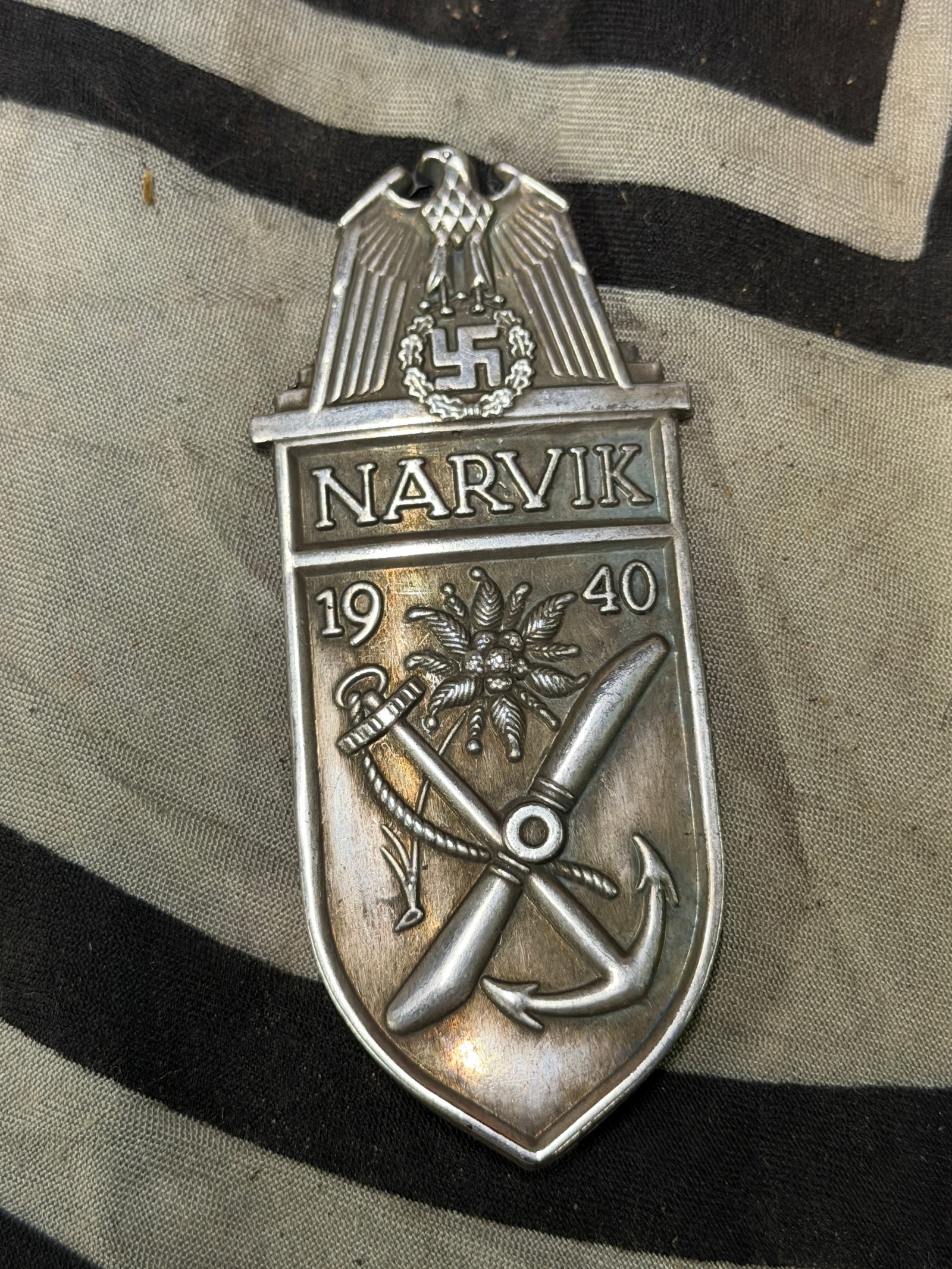 WWII Germany Narvik (Norway) Shield Badge in Zinc: WWII Germany Narvik (Norway) Shield Badge in Zinc. First issued on 19th August 1940, the Narvik shield was the first of a series of shield badges. It was awarded to all members of the Army, Navy & Air
