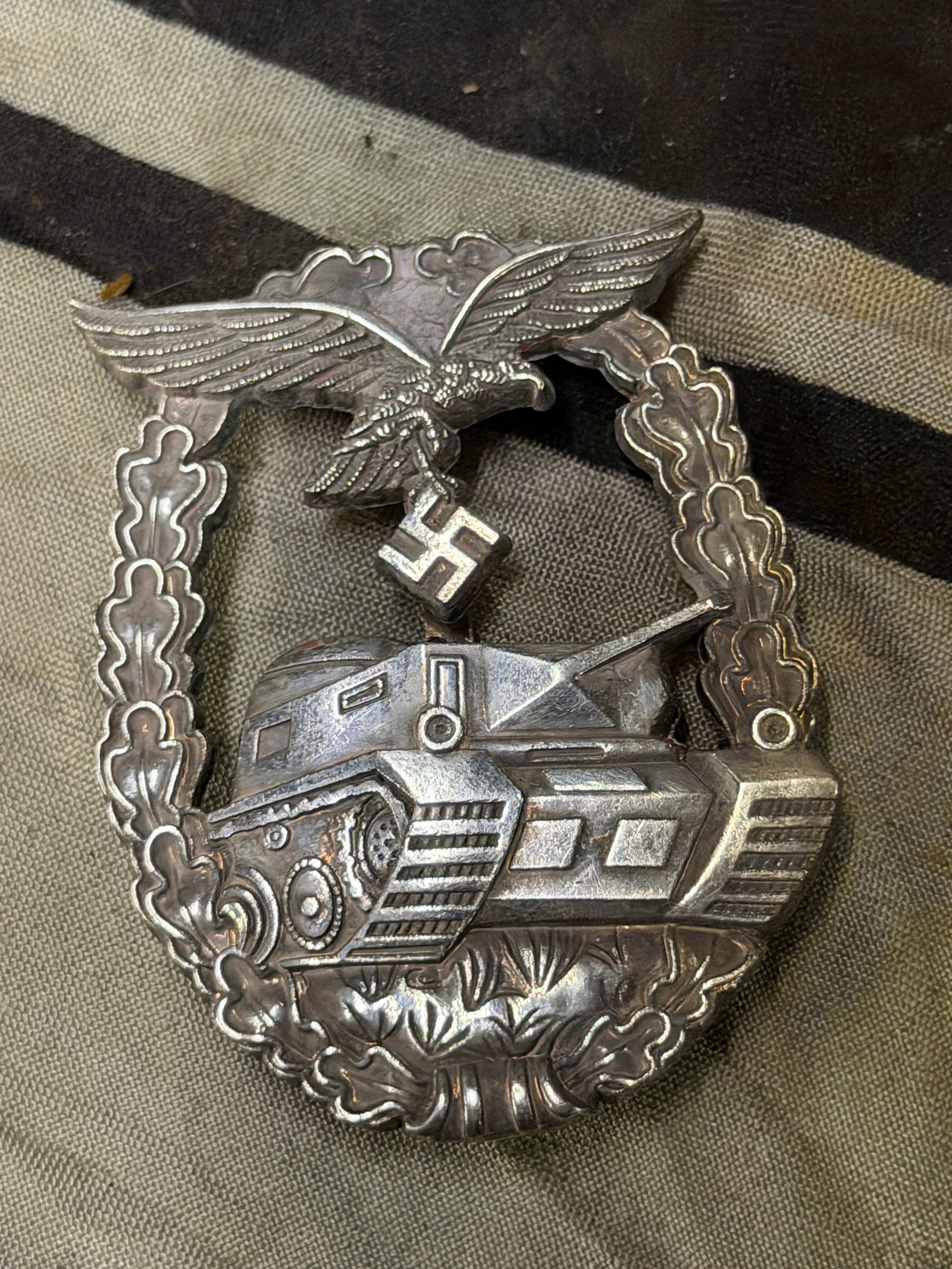 WWII GERMAN REICH LUFTWAFFE TANK ASSAULT BADGE: WWII GERMAN REICH LUFTWAFFE TANK ASSAULT BADGE. Eagle riveted to oak leaf wreath. Silvered zinc construction. Measures 2 1/4 inches. Very good condition. No marks.